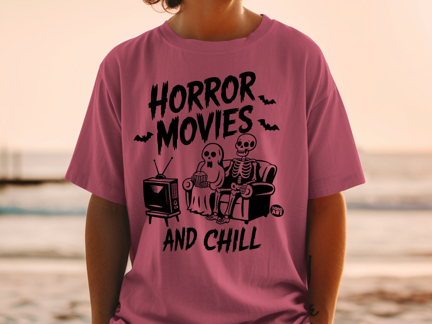 Pink t-shirt with "Horror Movies and Chill" skeleton graphic.
