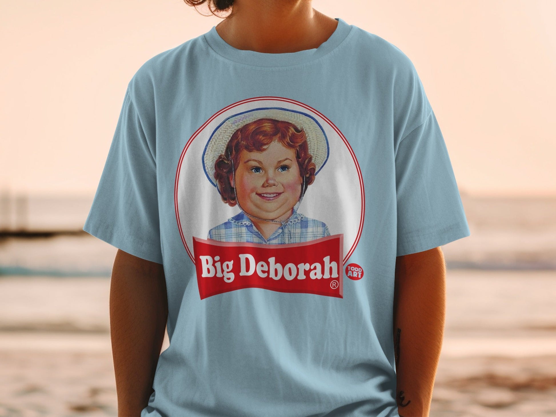 Light blue t-shirt with "Big Deborah" logo featuring a smiling girl.