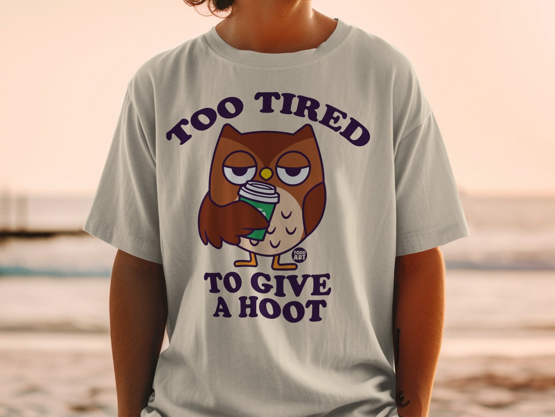 T-shirt with brown owl holding coffee cup and text "TOO TIRED TO GIVE A HOOT".