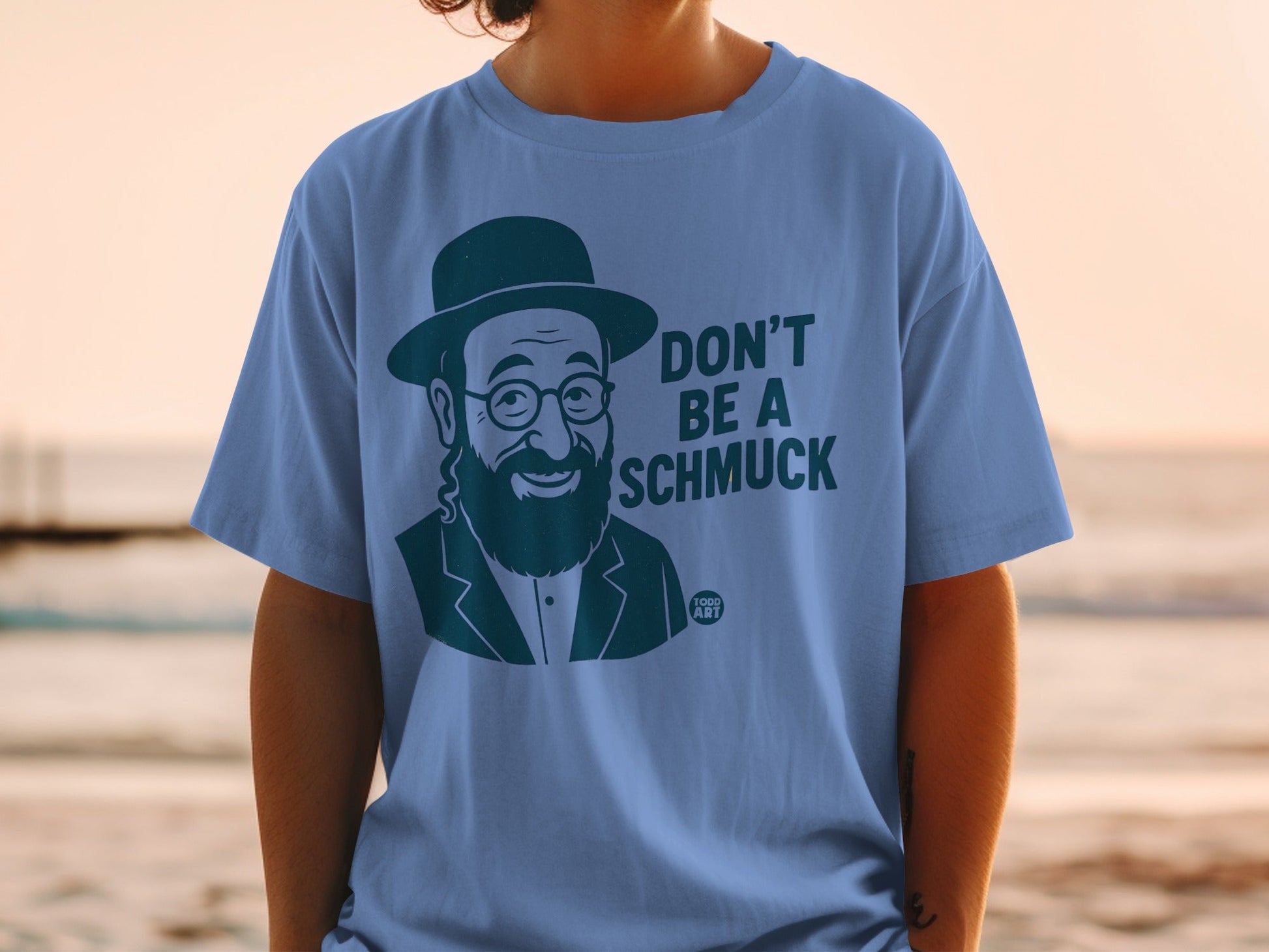 Blue t-shirt with a cartoon man wearing a hat and glasses saying "Don't be a schmuck".