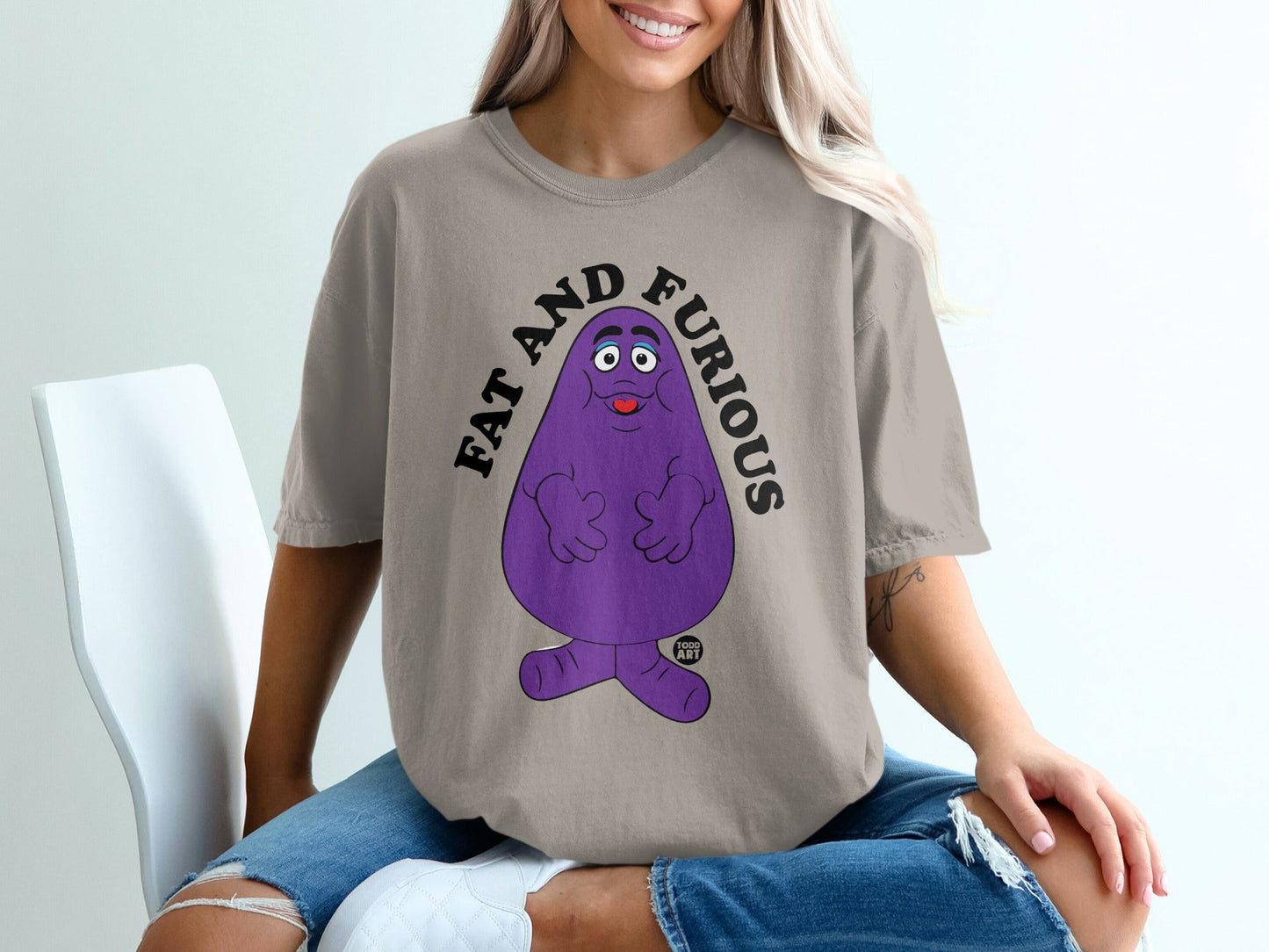 Purple Grimace character with "FAT AND FURIOUS" text on a t-shirt.