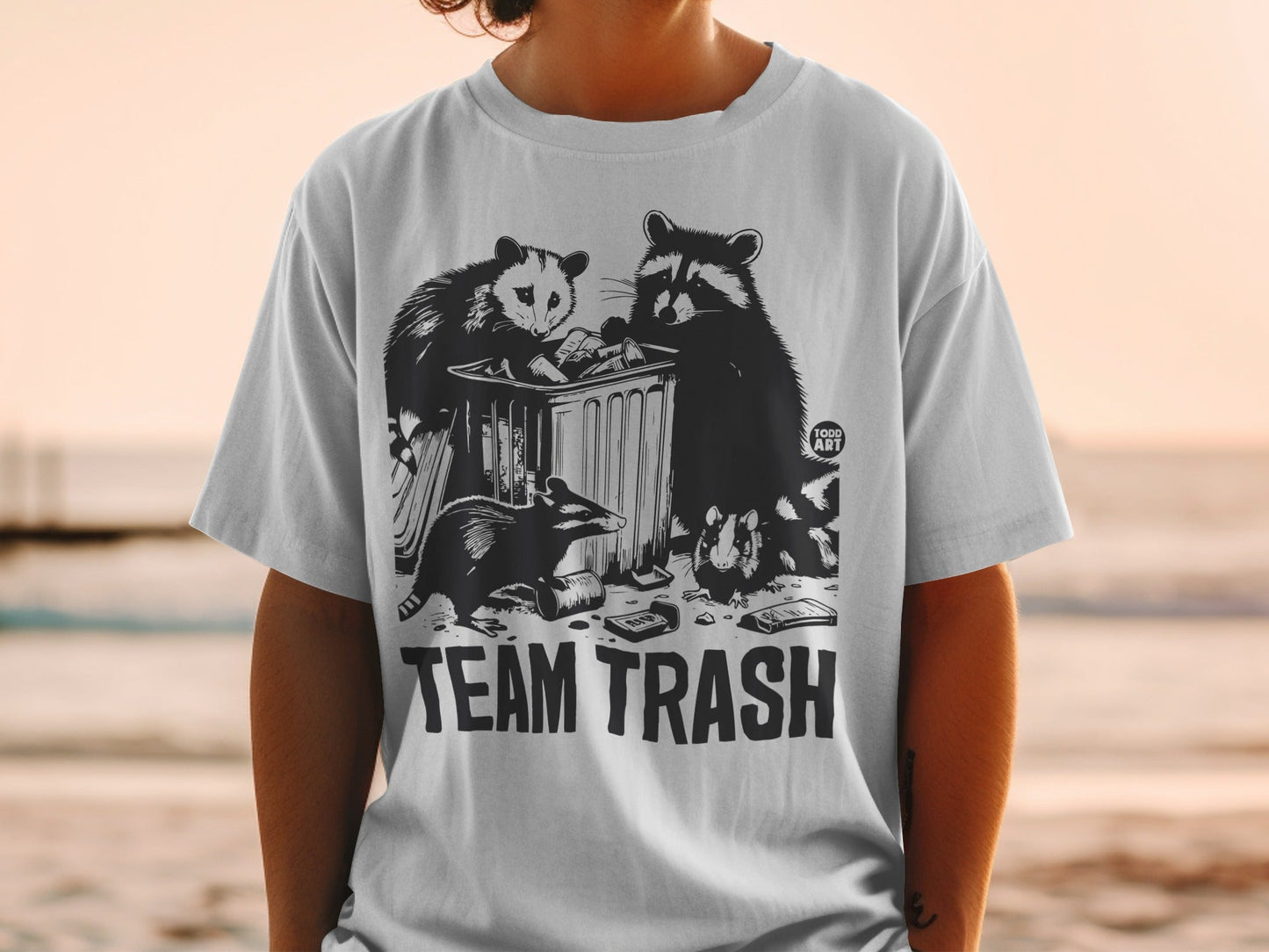 T-shirt with "TEAM TRASH" text and raccoons and opossum in a trash can.