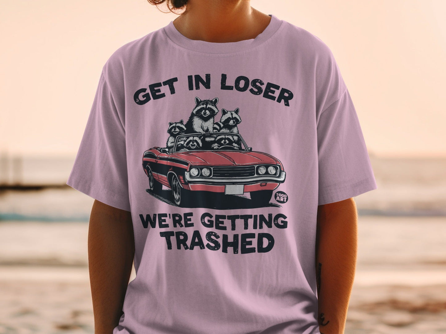 T-shirt with raccoons in a convertible, text "GET IN LOSER WE'RE GETTING TRASHED".