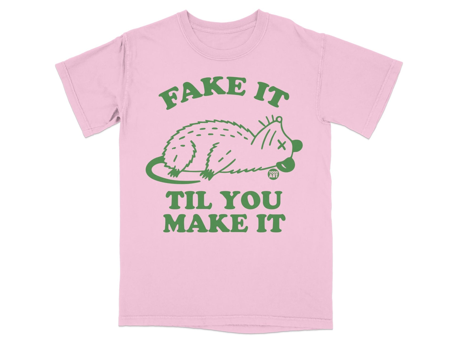 Pink t-shirt with green text and a drawing of a possum saying "Fake It Til You Make It".