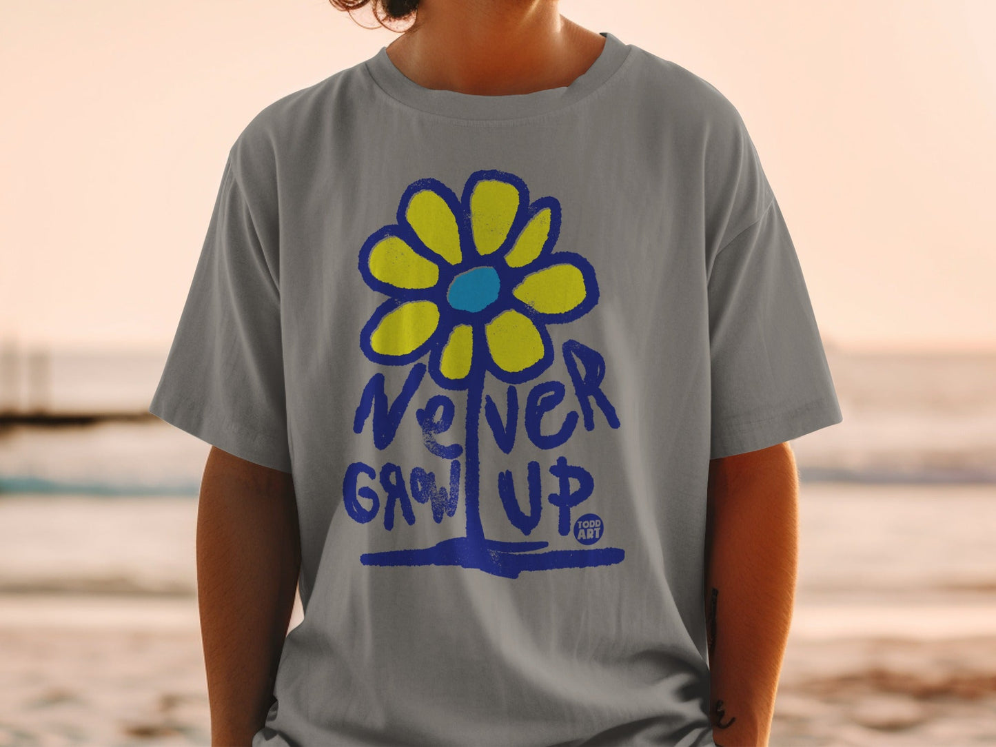 Gray t-shirt with blue and yellow flower graphic and "Never Grow Up" text.