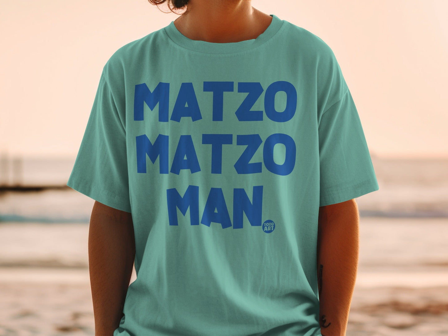 Teal t-shirt with "MATZO MATZO MAN" and "YOGG ART" logo.