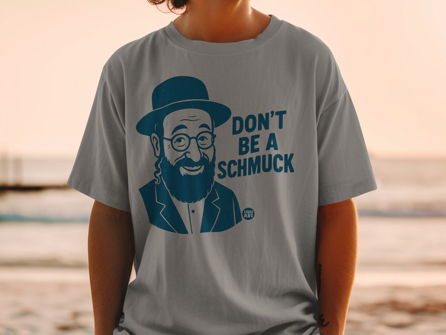 Grey t-shirt with cartoon man wearing hat and glasses saying "Don't Be a Schmuck."