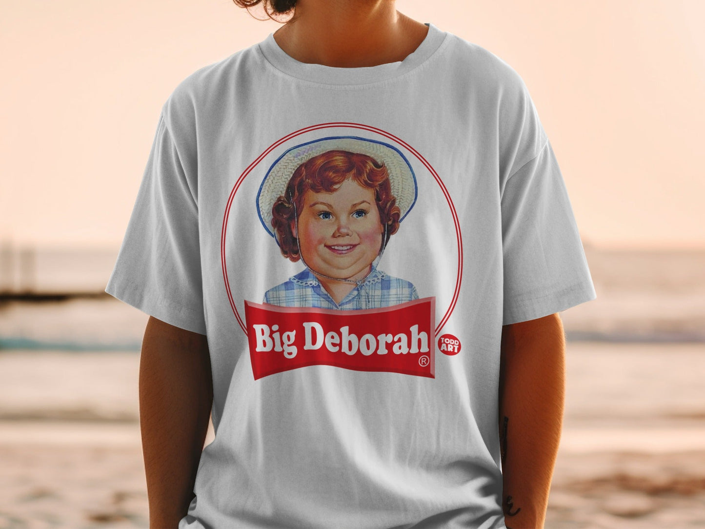 White t-shirt with "Big Deborah" logo featuring a young girl in a hat.