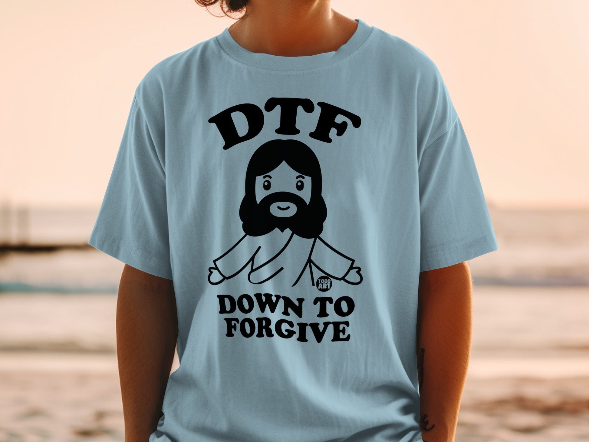 Light blue t-shirt with a cartoon Jesus and the text "DTF DOWN TO FORGIVE".