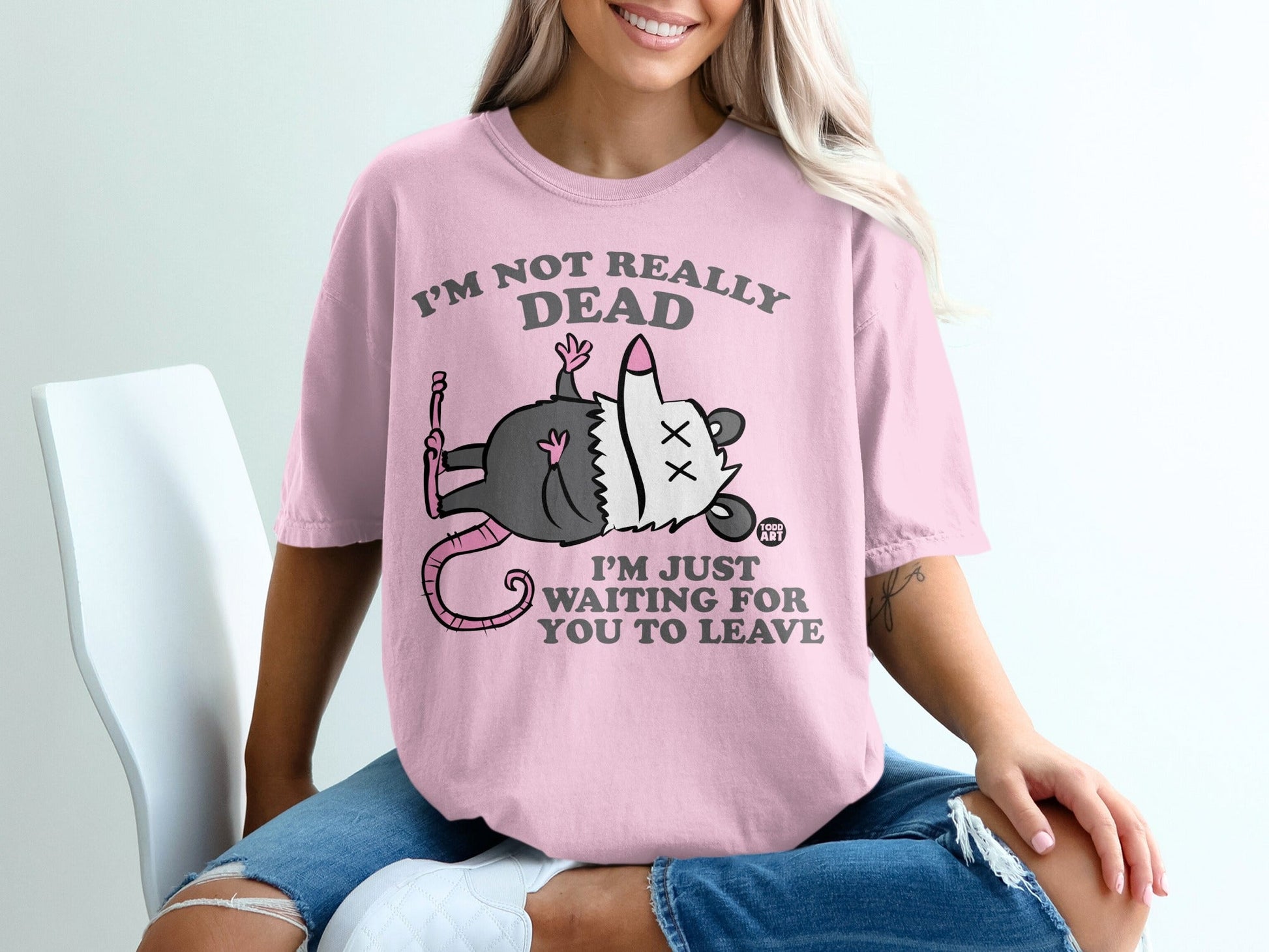 Pink t-shirt with cartoon possum and text "I'M NOT REALLY DEAD I'M JUST WAITING FOR YOU TO LEAVE".