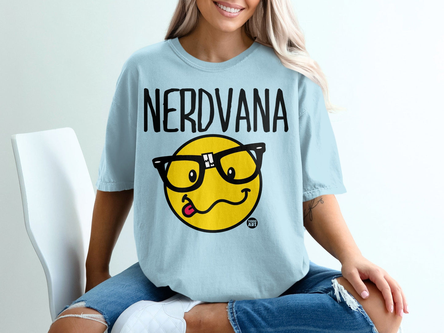 Light blue t-shirt with "NERDVANA" and a smiling emoji with glasses and tongue out.