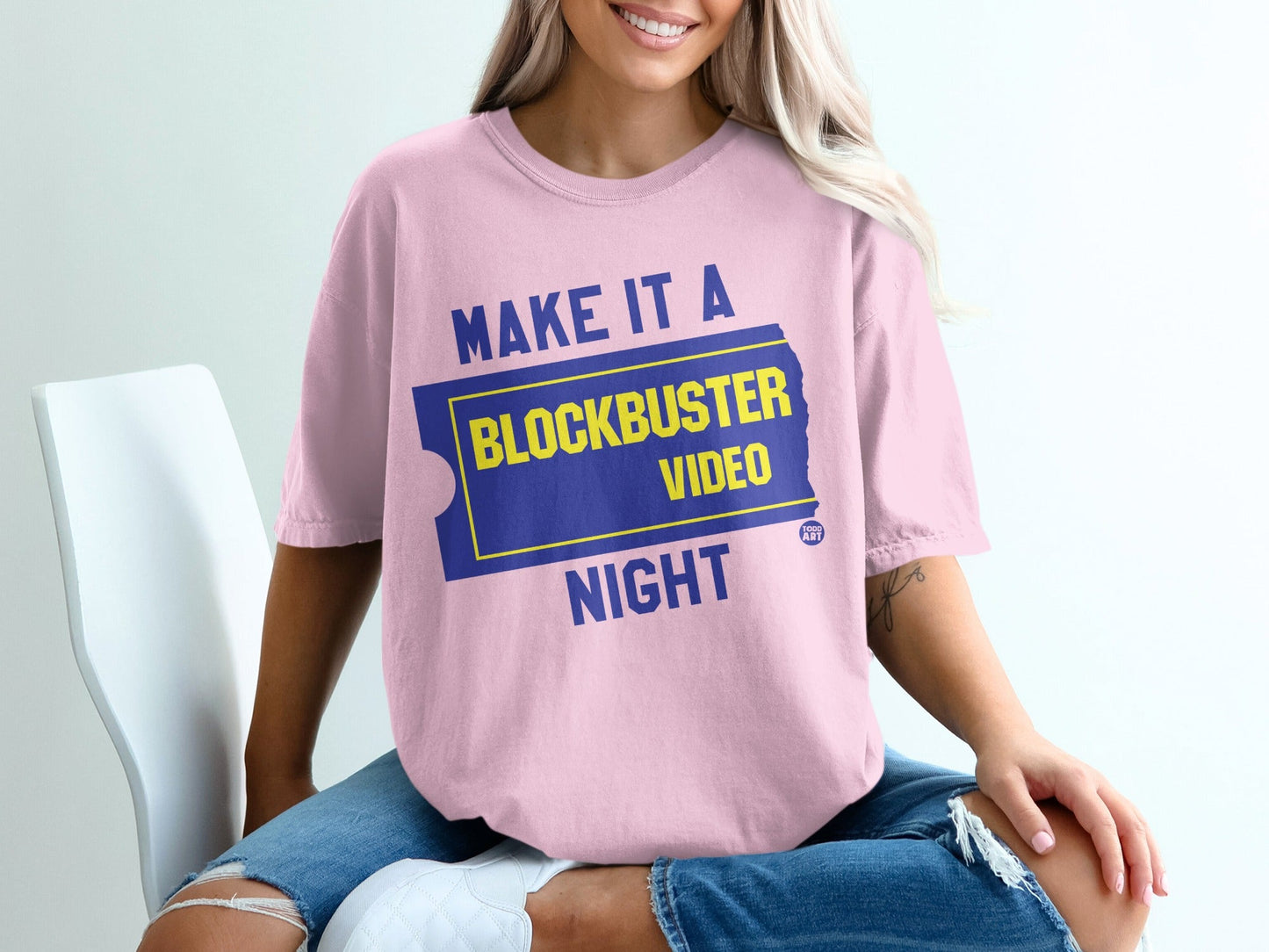 Pink t-shirt with "Make It A Blockbuster Night" text on a ticket graphic.