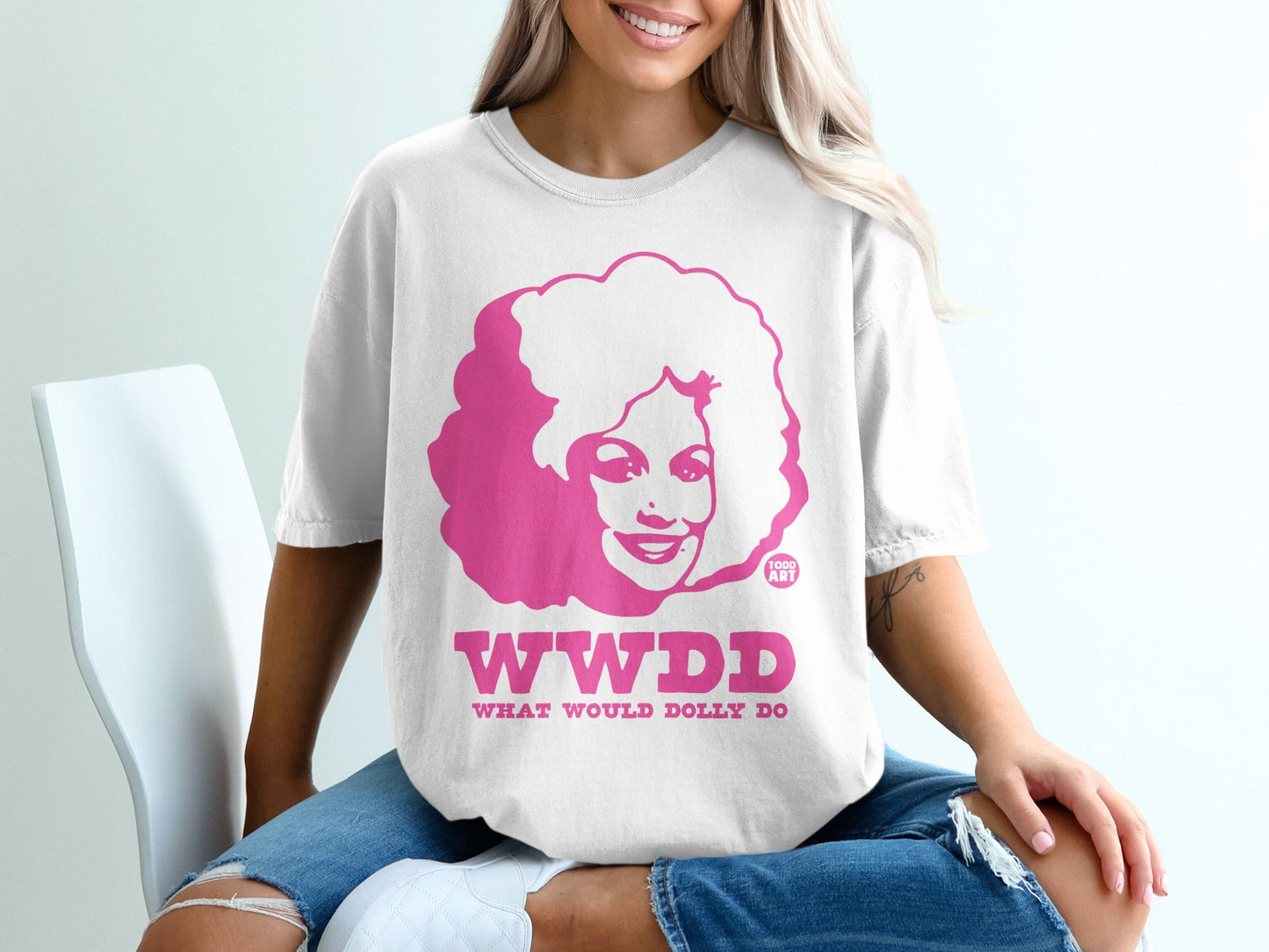 White t-shirt with pink "WWDD WHAT WOULD DOLLY" text and Dolly Parton's face.
