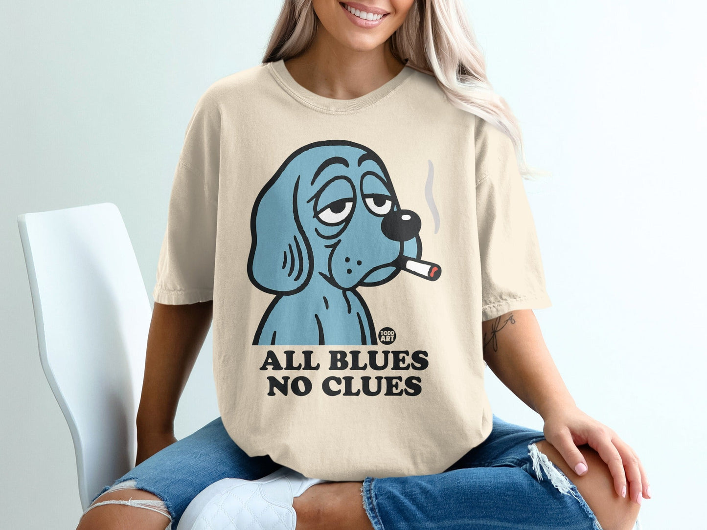 Blue cartoon dog smoking cigarette on t-shirt, "ALL BLUES NO CLUES" text.