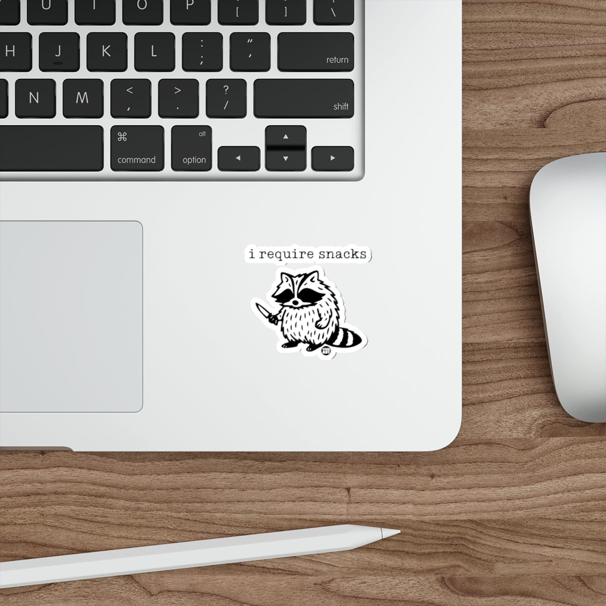Sticker of a raccoon holding a knife with the text "i require snacks".