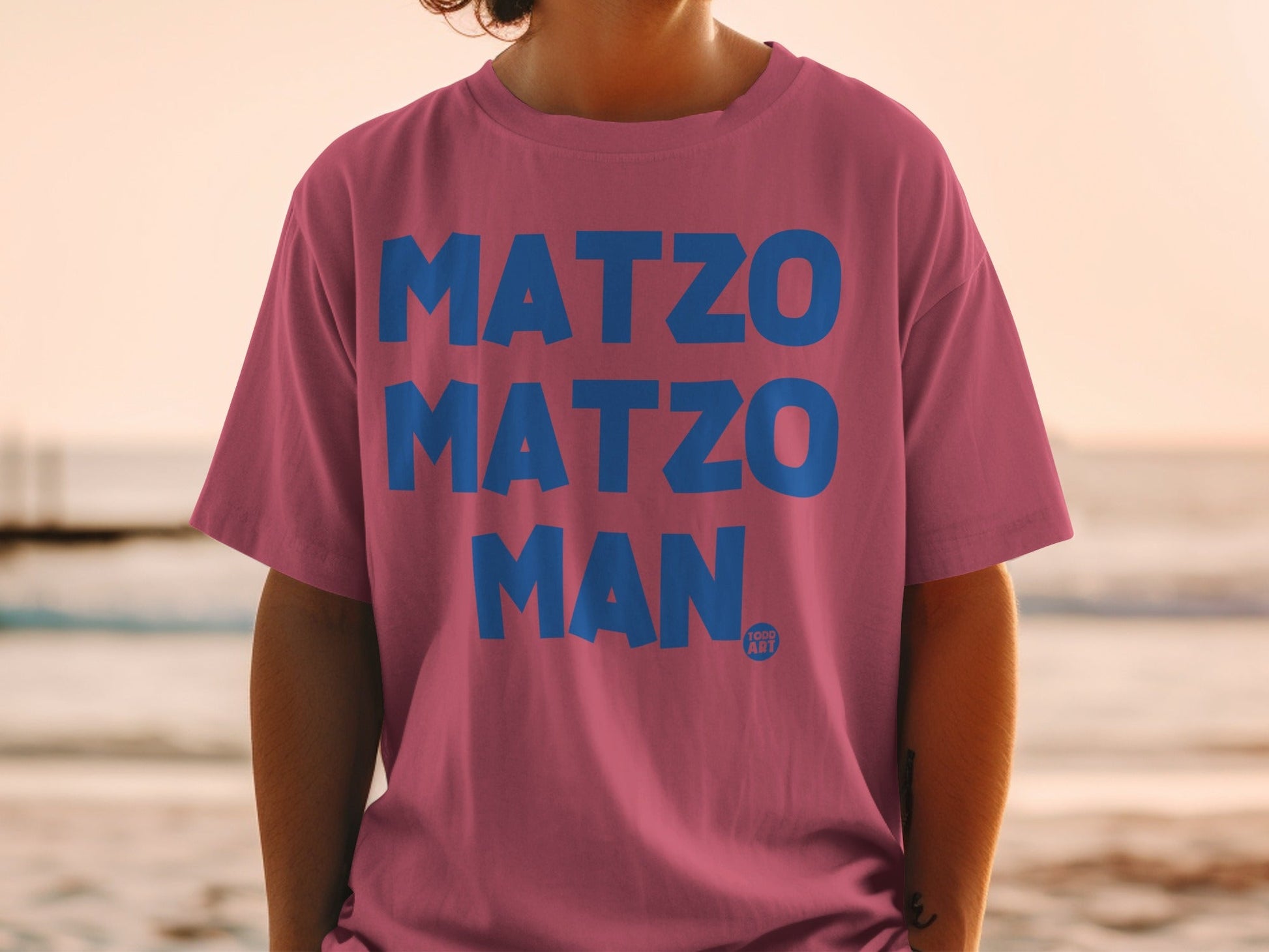 Pink t-shirt with blue text "MATZO MATZO MAN" and a small logo.