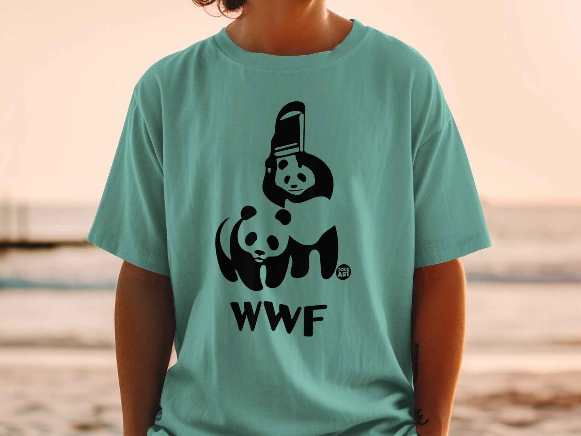 Black WWF logo with pandas on a teal t-shirt worn by a person.
