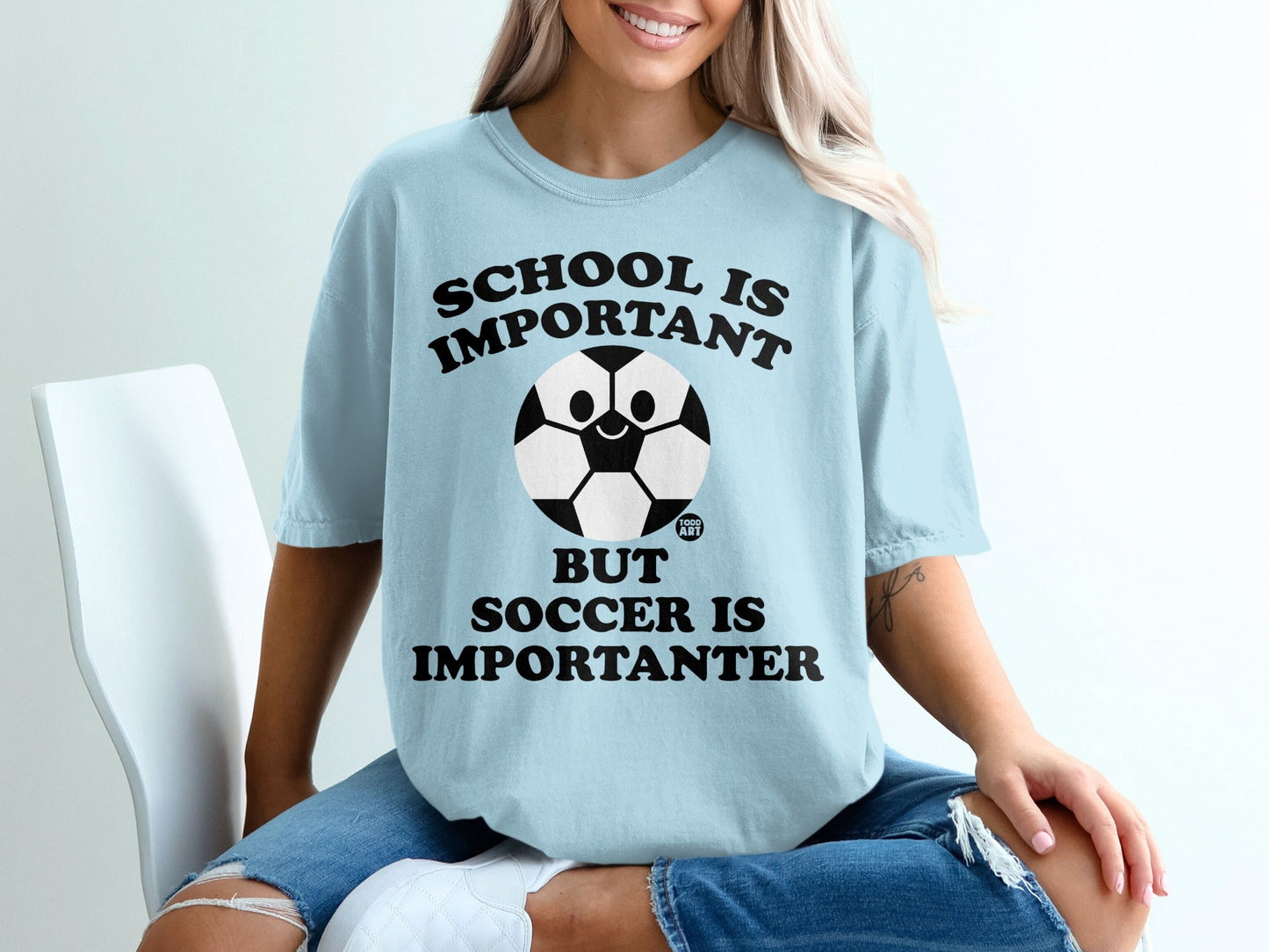 Light blue t-shirt with "School is important but soccer is importanter" text and soccer ball graphic.