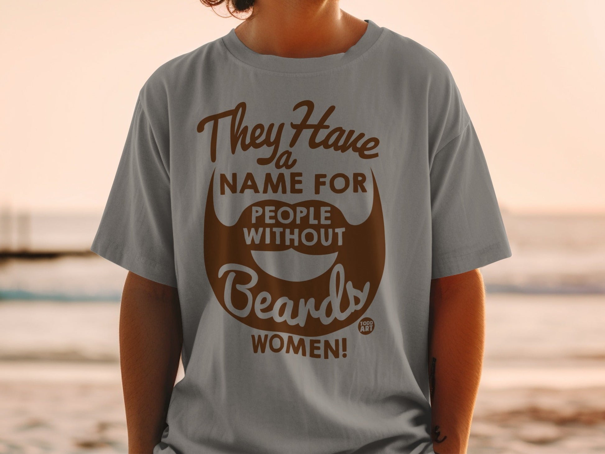 Grey t-shirt with brown text reading "They Have a Name For People Without Beards WOMEN!"