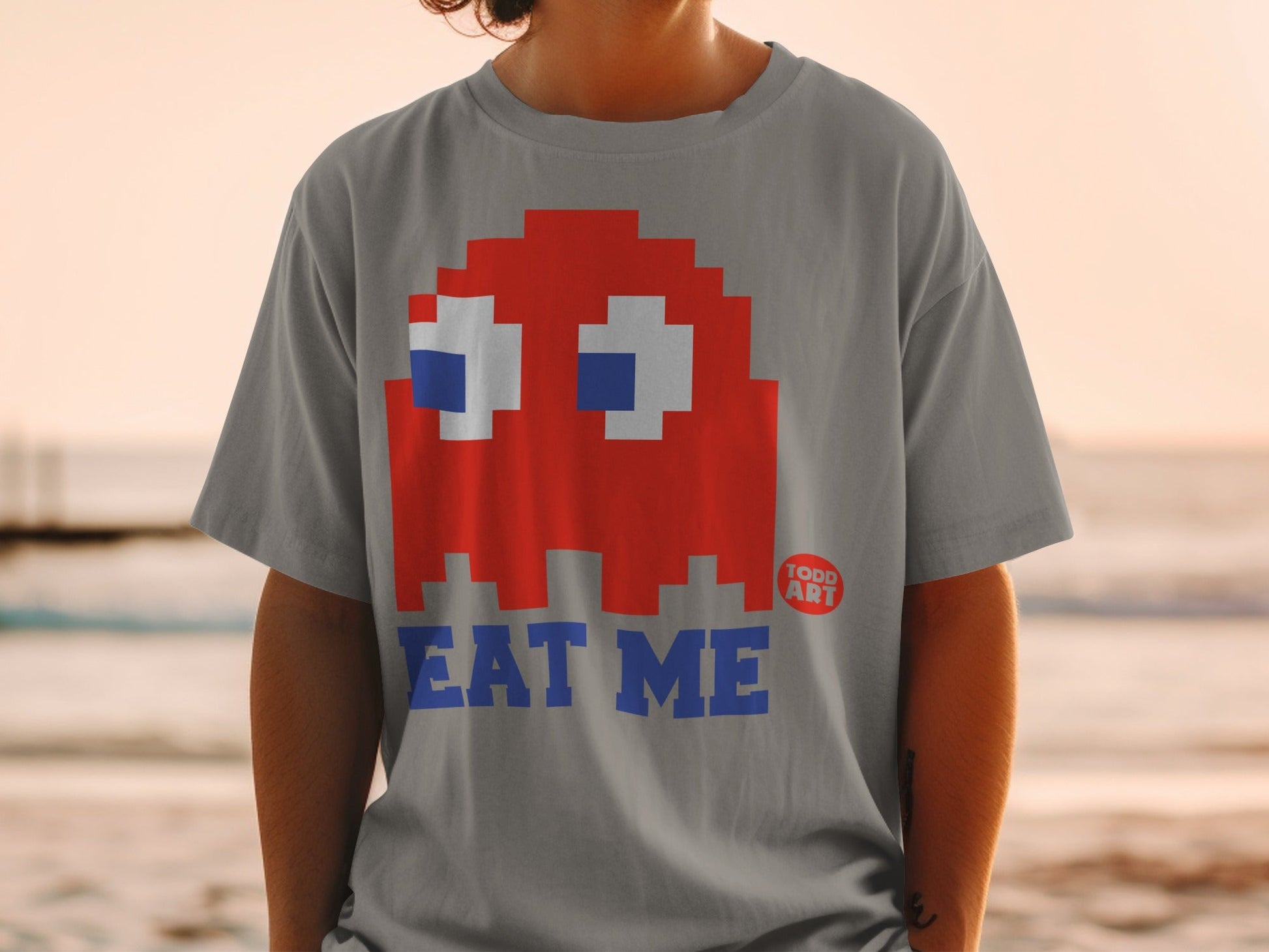Gray t-shirt with red Pac-Man ghost and "EAT ME" text.