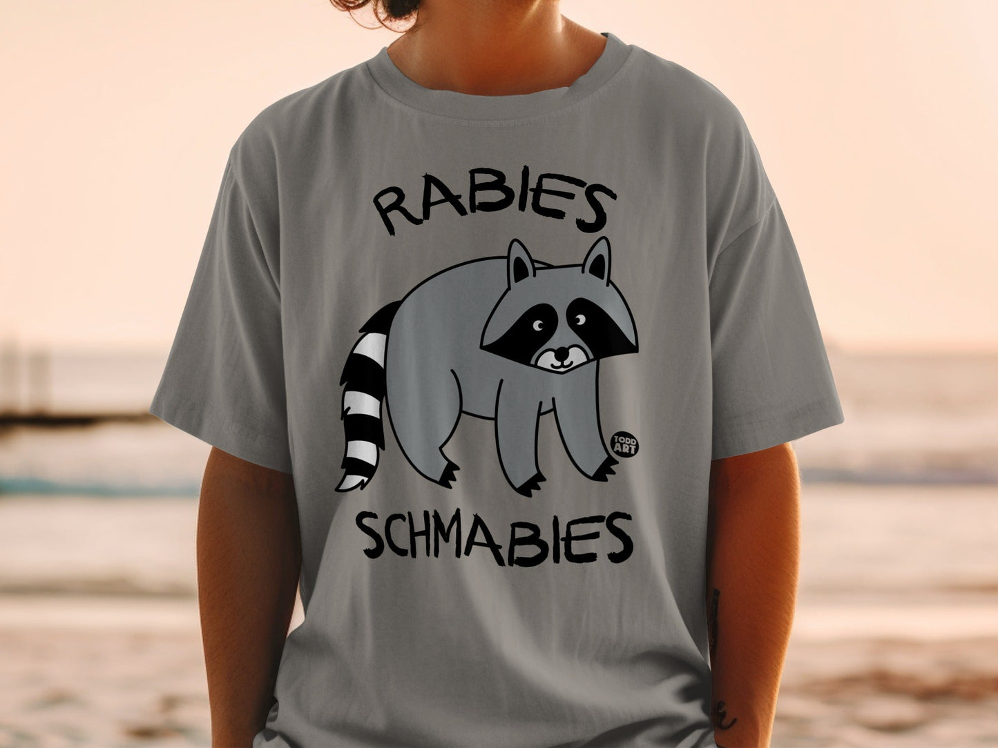 Gray t-shirt with raccoon graphic and text "RABIES SCHMABIES".