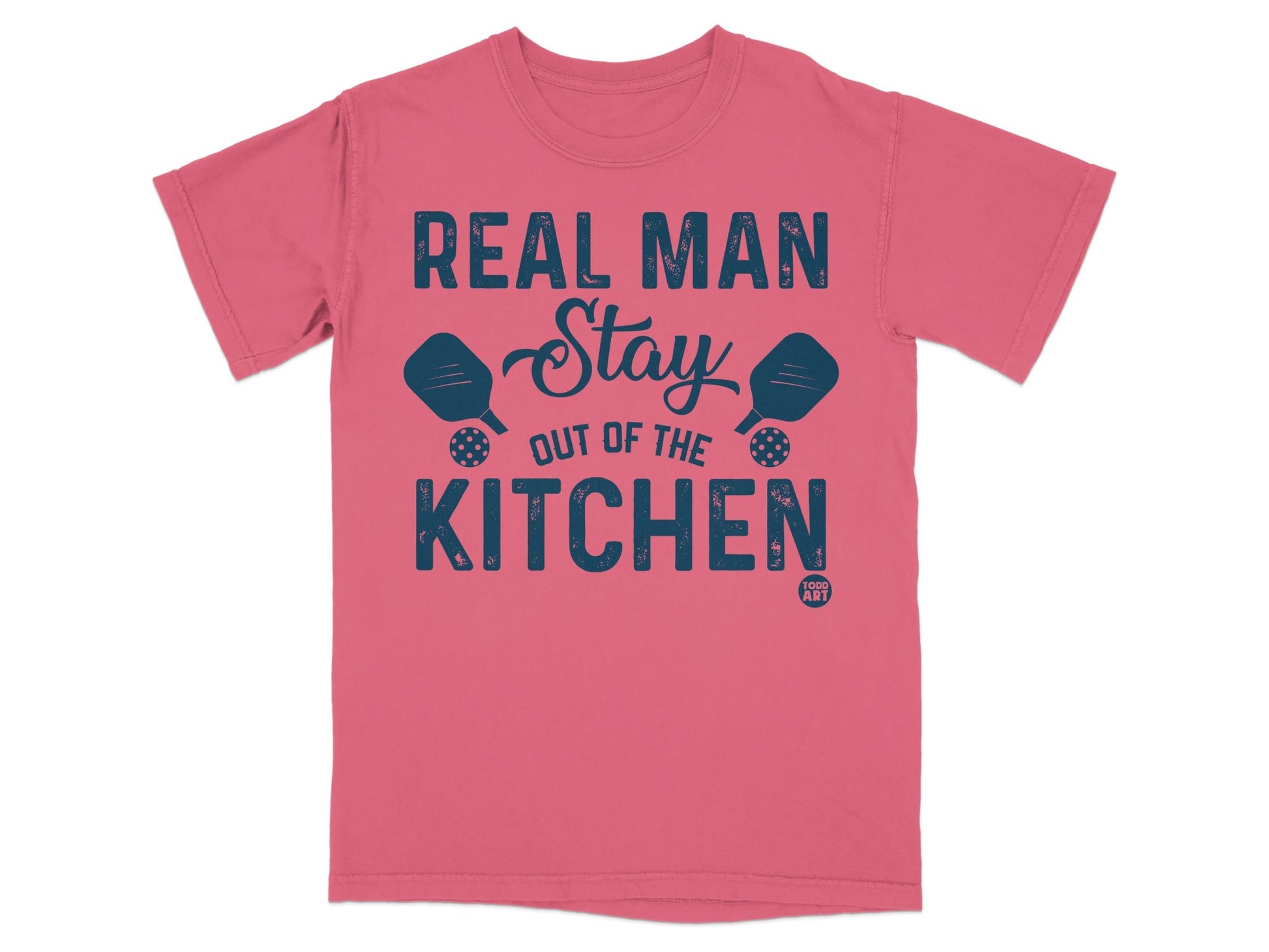 Coral t-shirt with "Real Man Stay Out of the Kitchen" text and pickleball paddles.