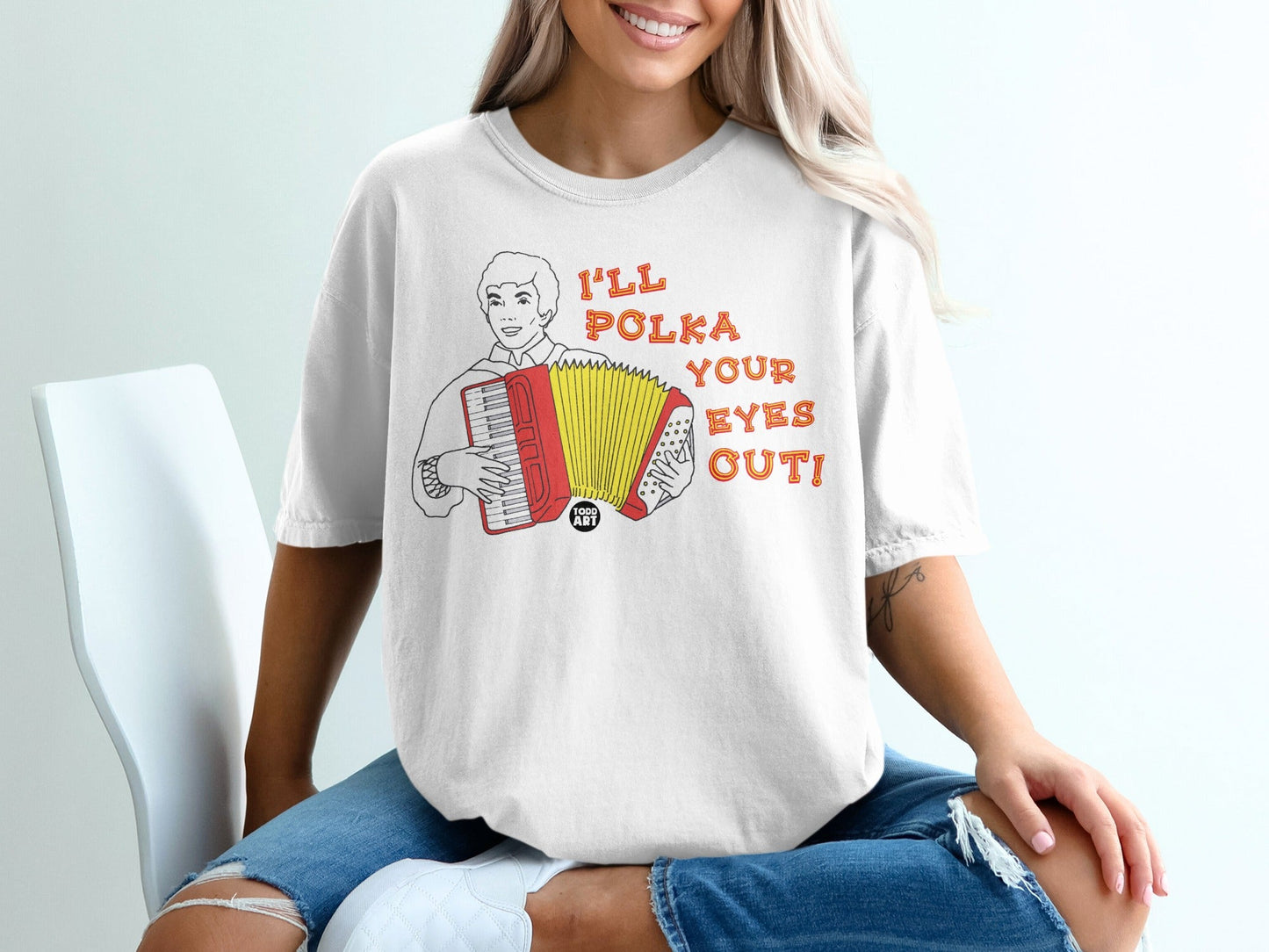 White t-shirt with graphic of accordion player and text "I'LL POLKA YOUR EYES OUT!".