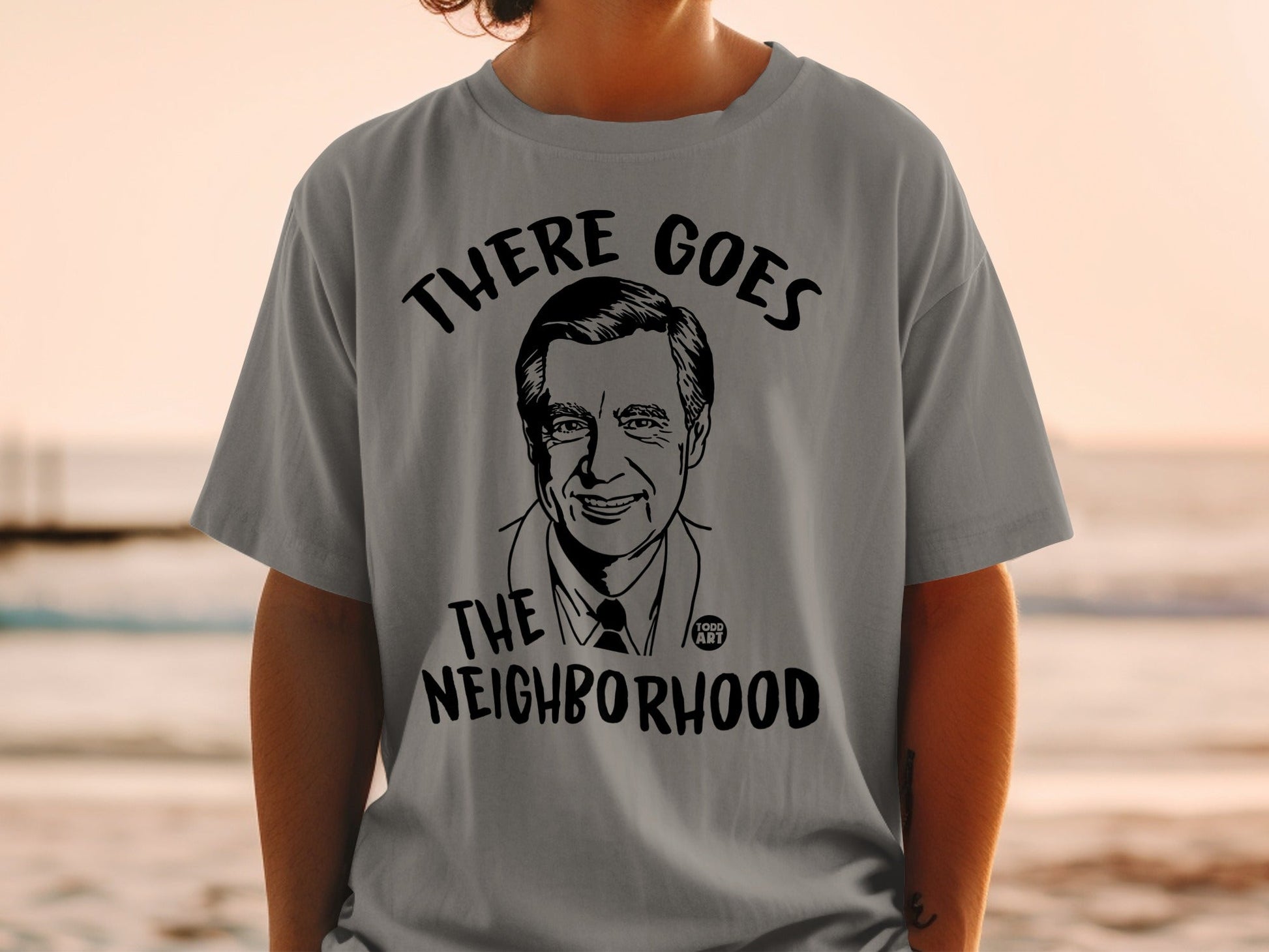 Fred Rogers graphic on a gray t-shirt with "THERE GOES THE NEIGHBORHOOD" text.
