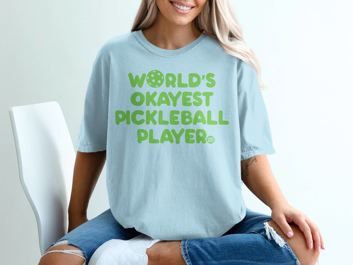 Light blue t-shirt with "WORLD'S OKAYEST PICKLEBALL PLAYER" in green text.