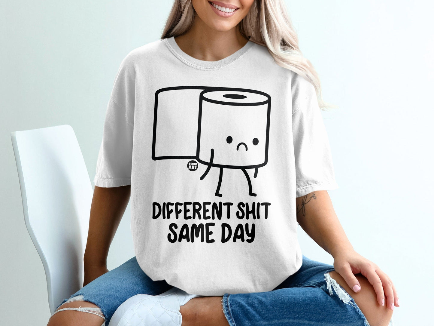 White t-shirt with sad toilet paper roll saying "DIFFERENT SHIT SAME DAY".