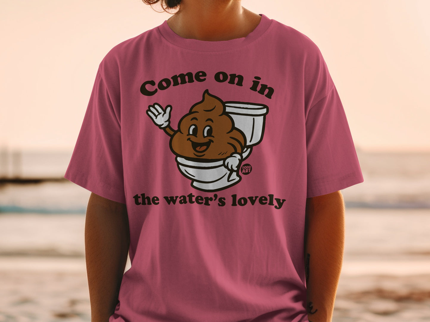 Pink t-shirt with cartoon brown toilet with happy face, "Come on in the water's lovely" text.