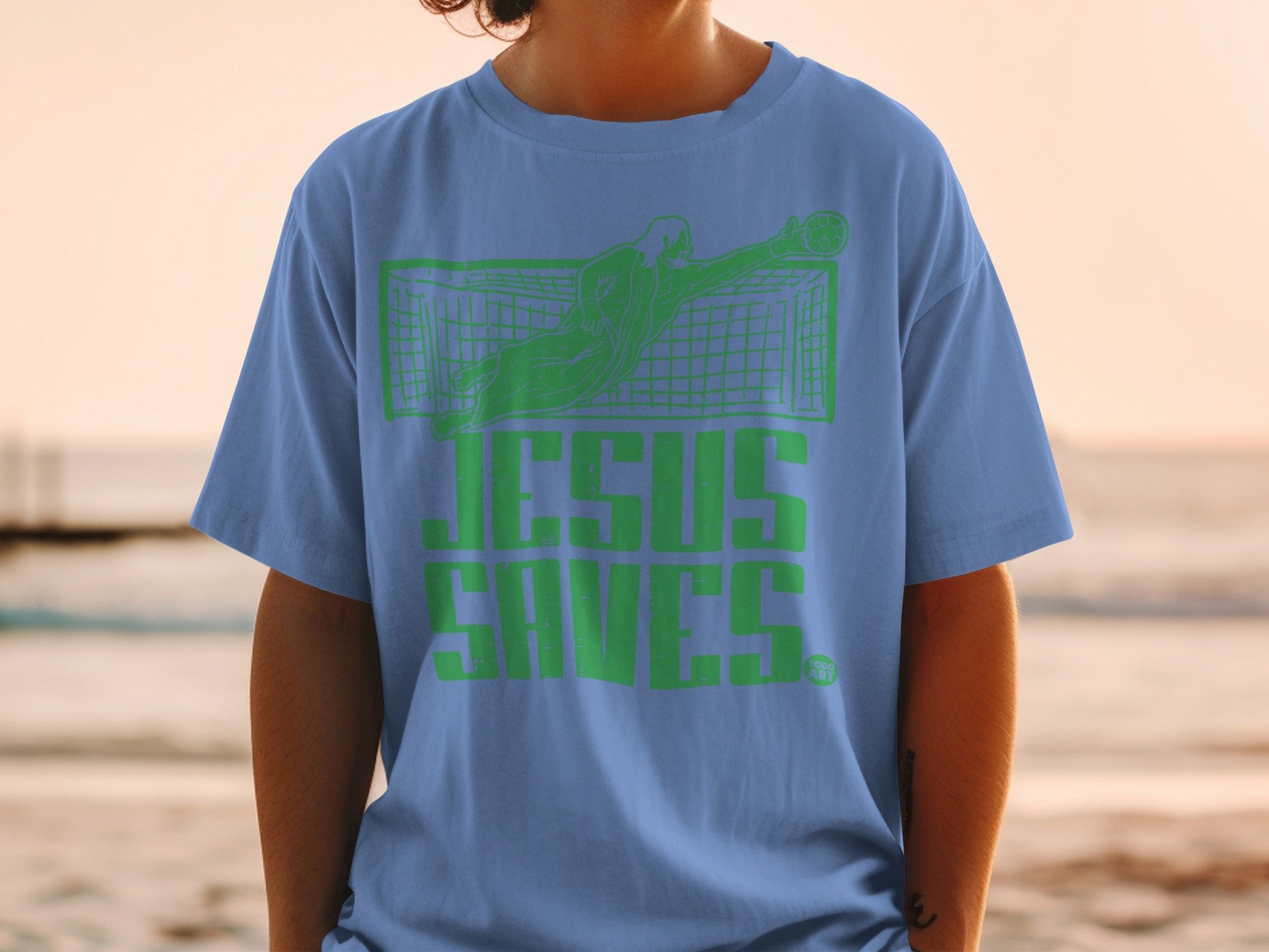 Light blue t-shirt with green text "JESUS SAVES" and soccer goalie graphic.