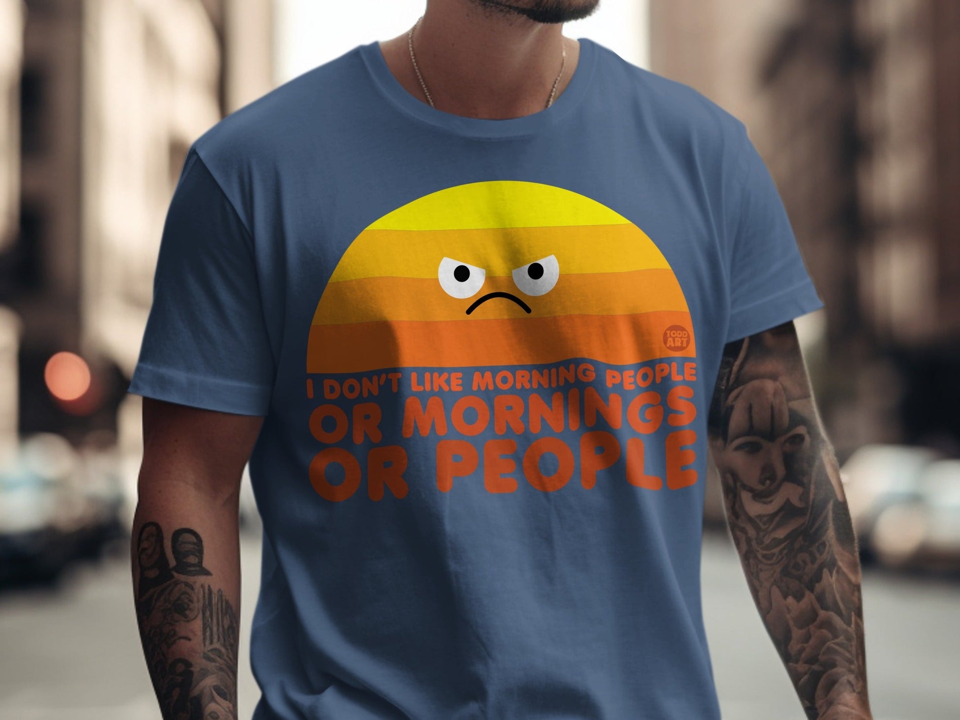 Blue t-shirt with orange sunrise graphic and "I don't like morning people or people" text.