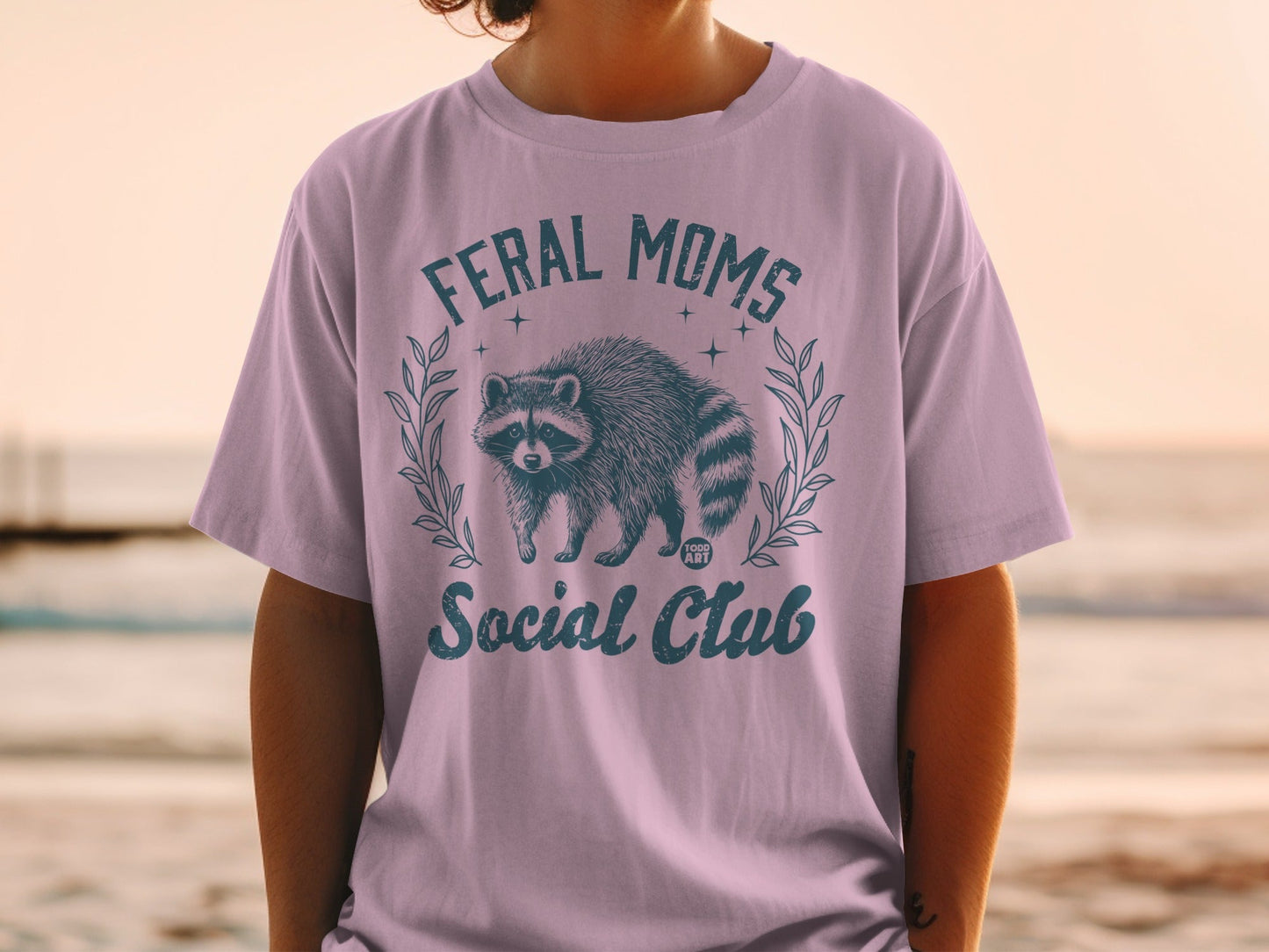 T-shirt with "Feral Moms Social Club" text and a raccoon graphic.