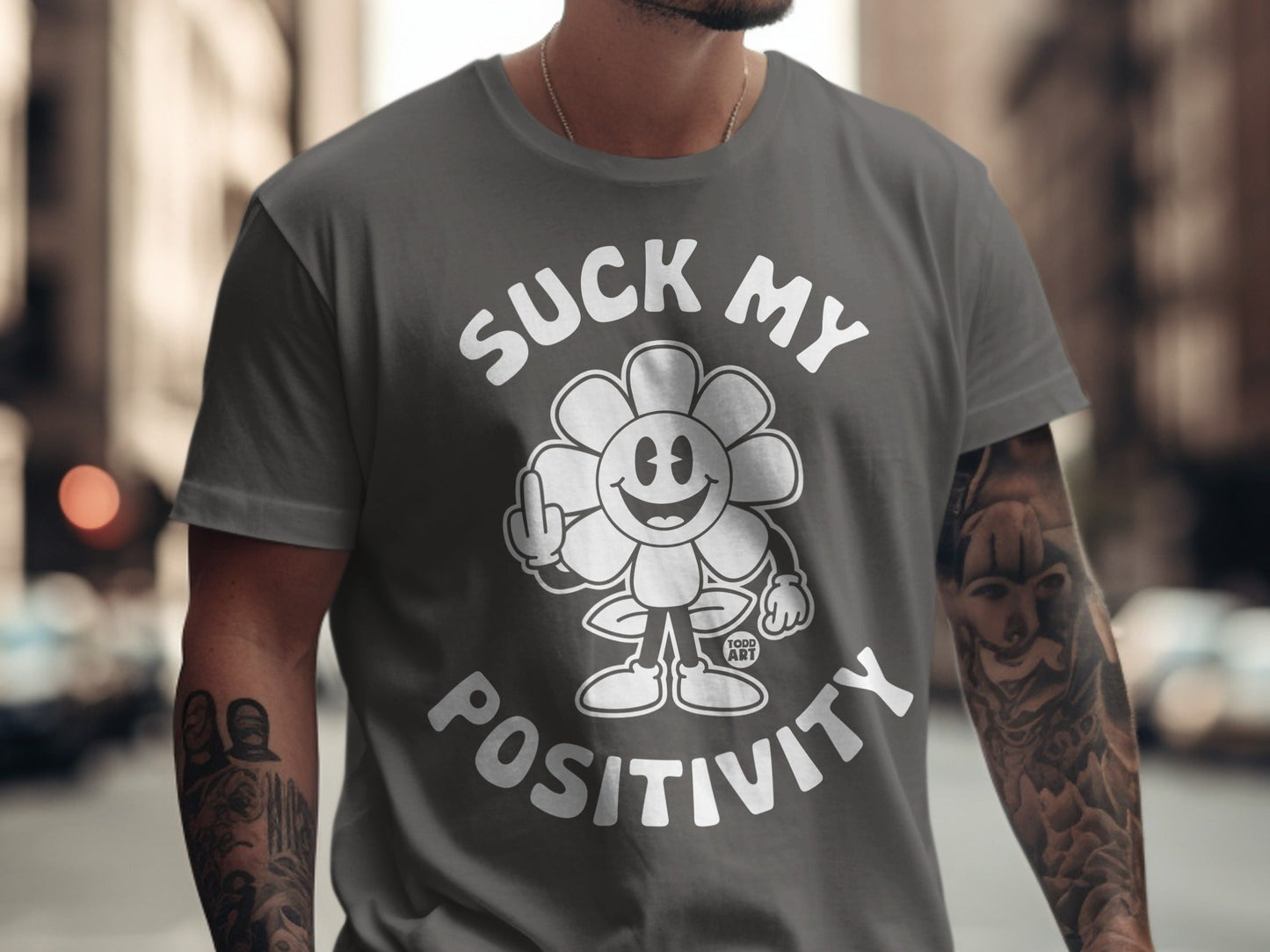 Gray t-shirt with a cartoon flower giving middle finger and text "Suck My Positivity".