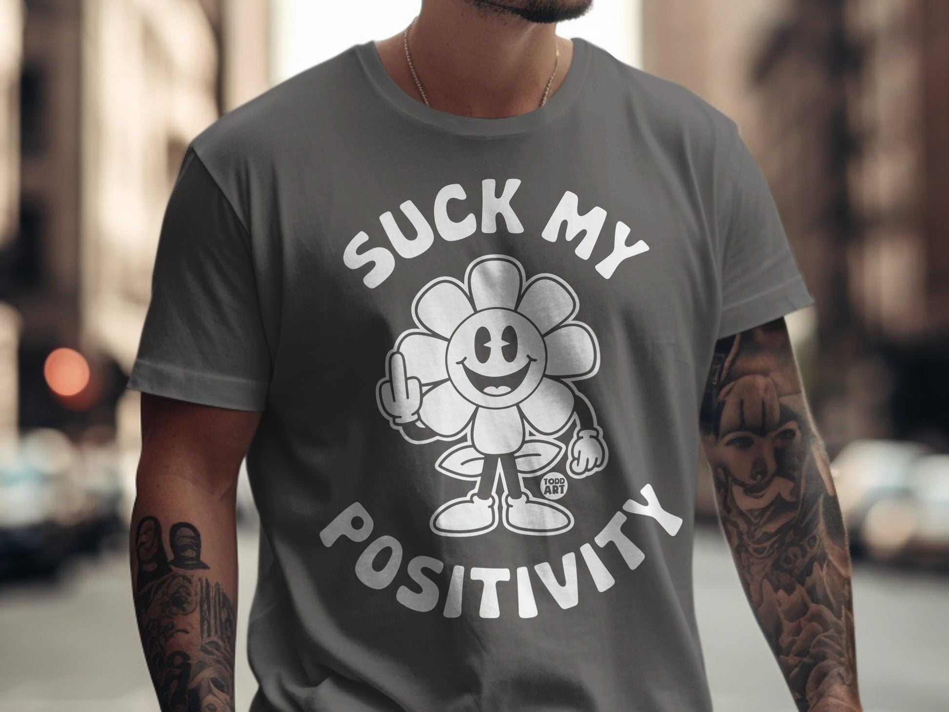 Gray t-shirt with a cartoon flower giving middle finger and text "Suck My Positivity".