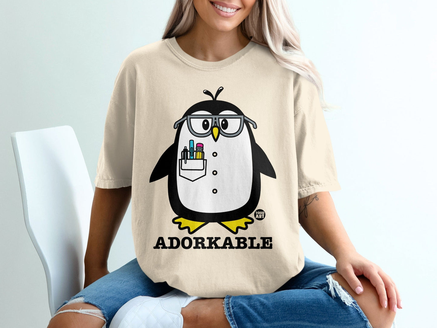 T-shirt with cartoon penguin wearing glasses and holding pencils.