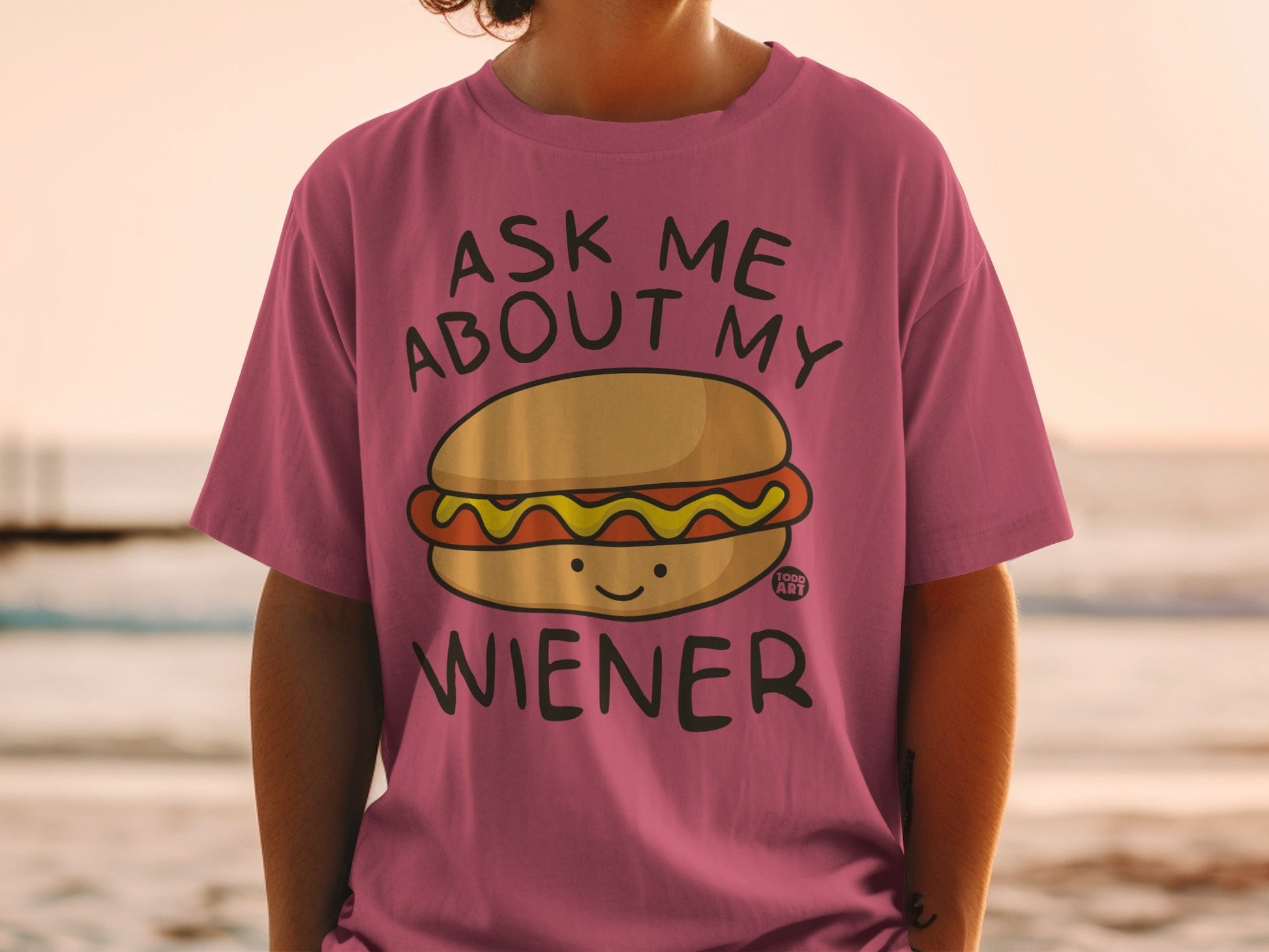 Pink t-shirt with cartoon hot dog and "Ask Me About My Wiener" text.