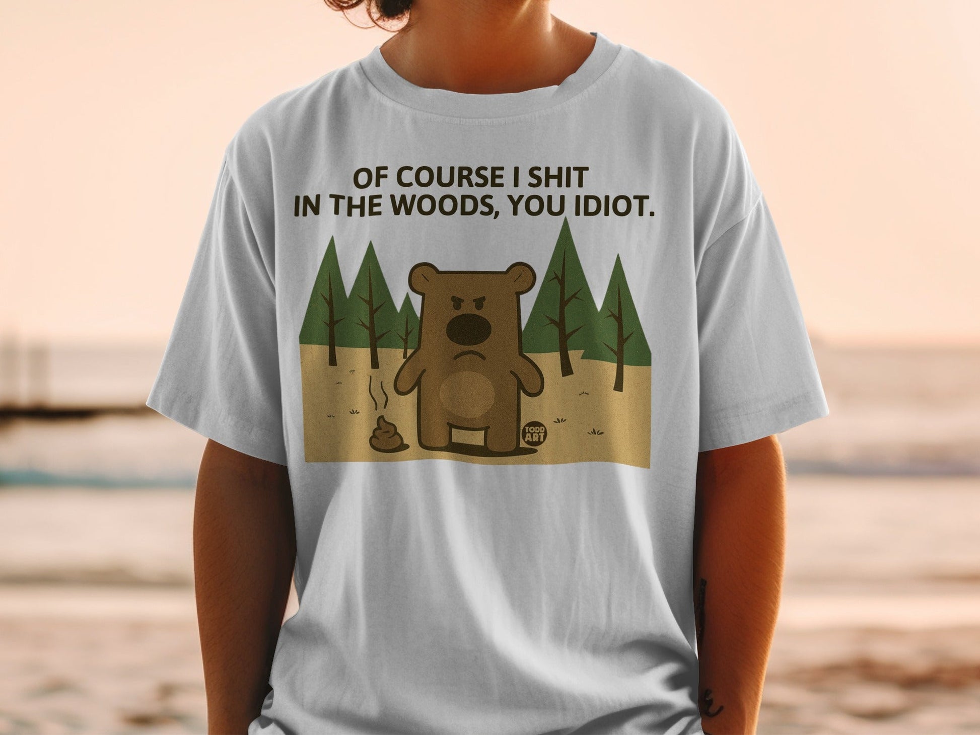 T-shirt with cartoon bear and pile of poop; text reads "Of course I shit in the woods, you idiot."