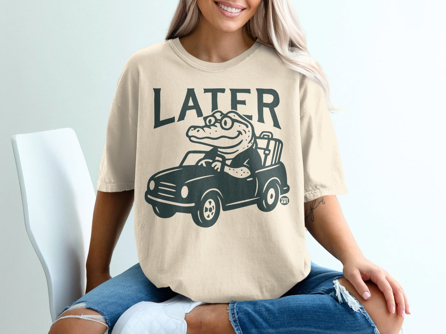 Cream t-shirt with alligator driving a car graphic and "LATER" text.