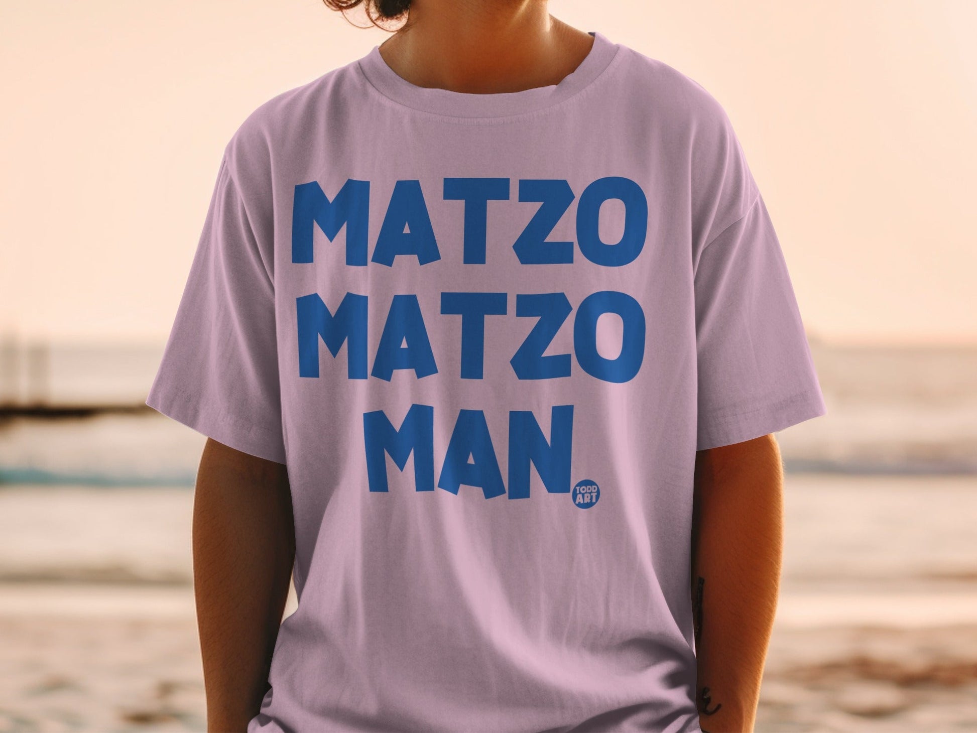 Purple t-shirt with blue text "MATZO MATZO MAN" and "1000 ART" logo.