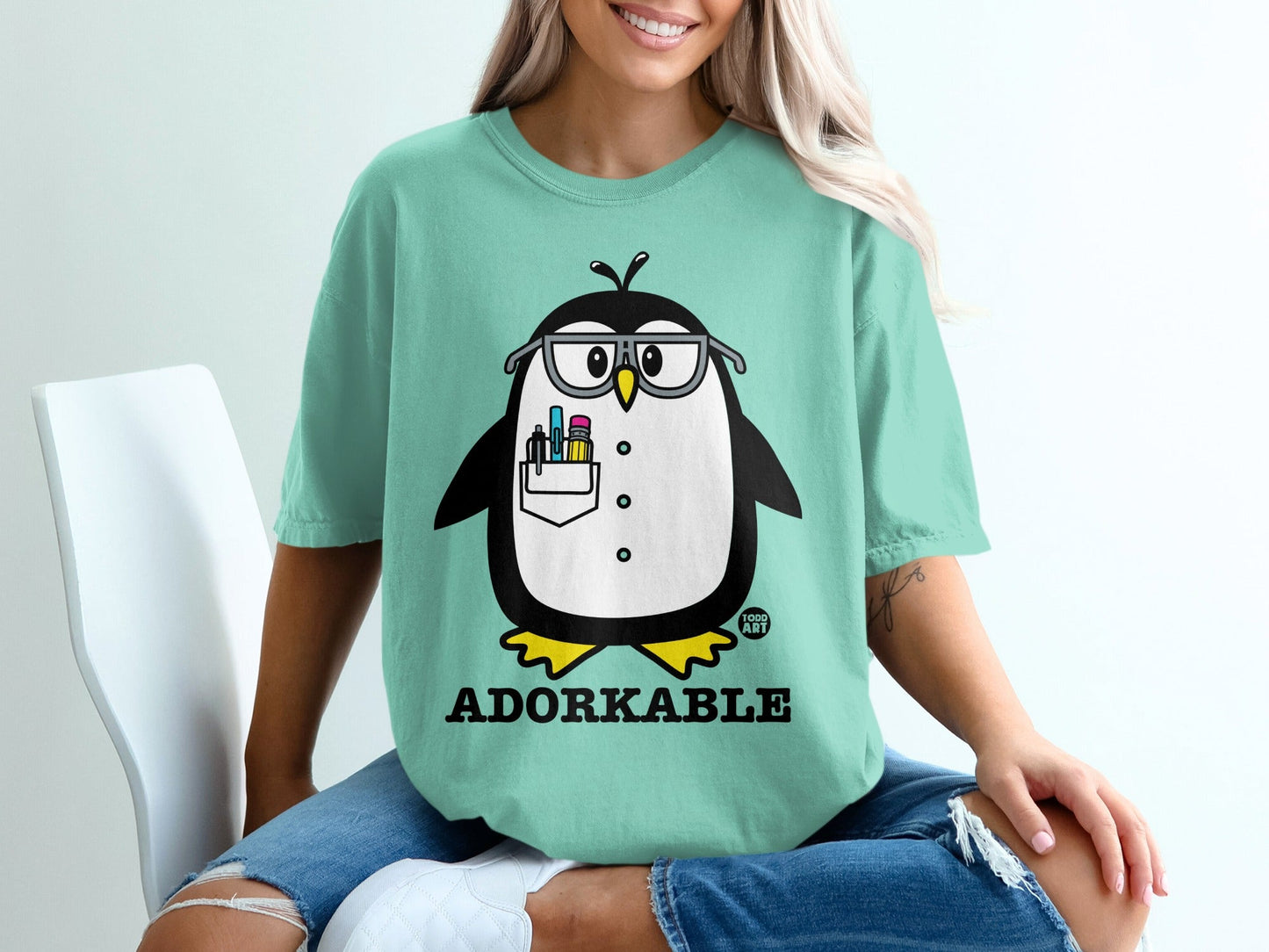 T-shirt with a cartoon penguin wearing glasses and holding pens.