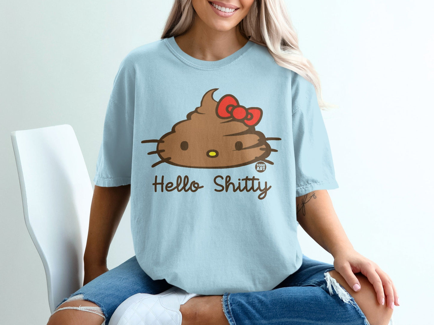 Light blue t-shirt with a cartoon brown poop emoji wearing a red bow, text "Hello Shitty".