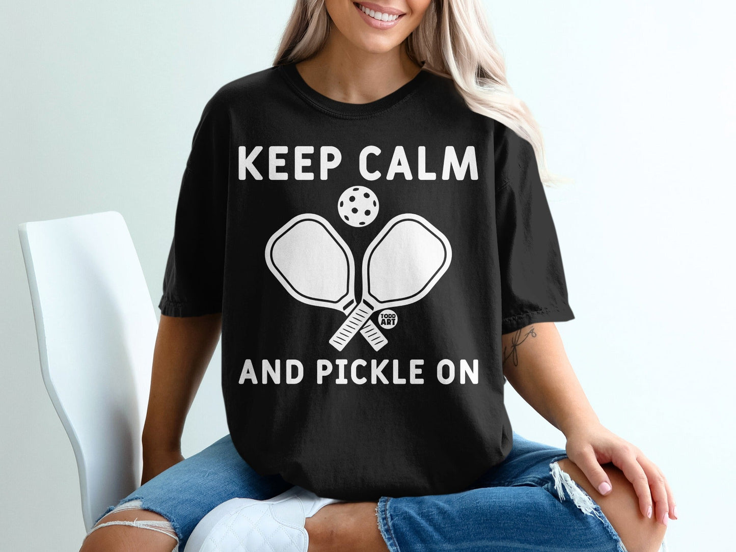 Black t-shirt with "KEEP CALM AND PICKLE ON" and crossed pickleball paddles.