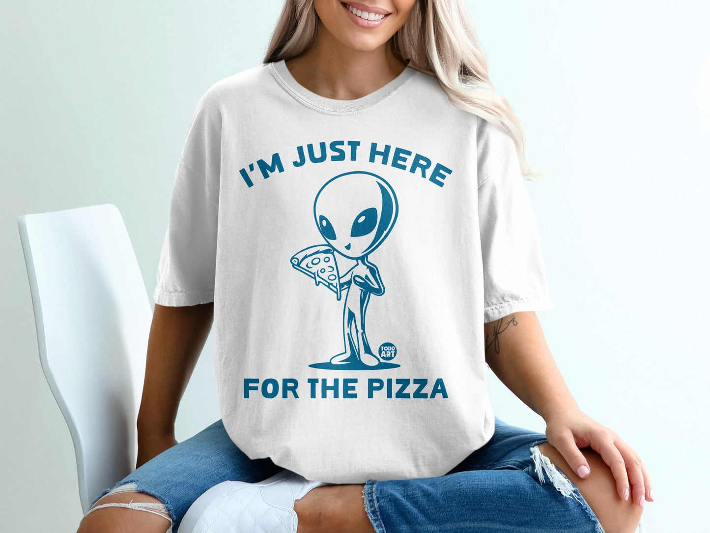 White t-shirt with an alien holding pizza and text "I'm Just Here For The Pizza".