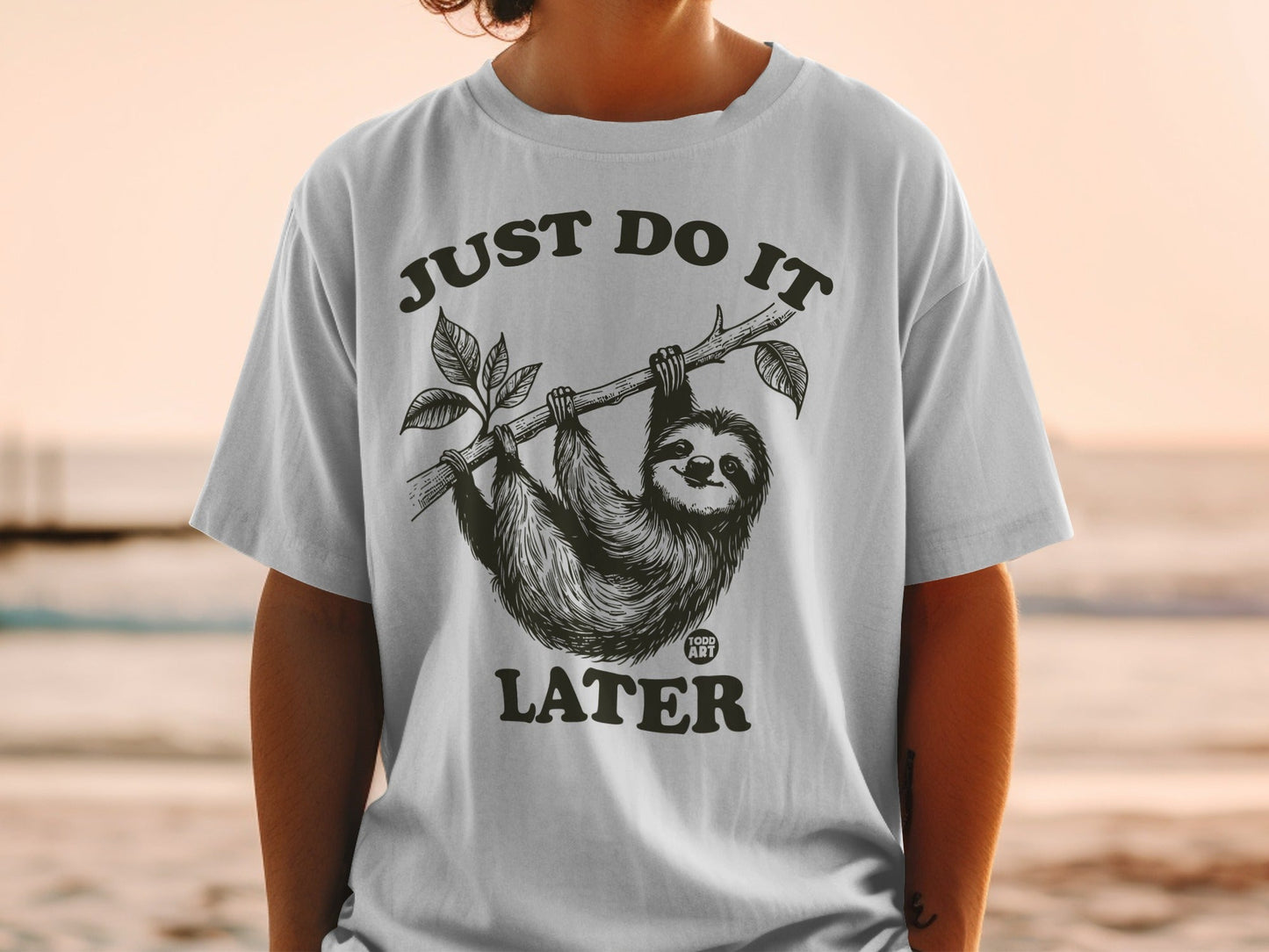 T-shirt with a smiling sloth hanging from a branch, text "JUST DO IT LATER".