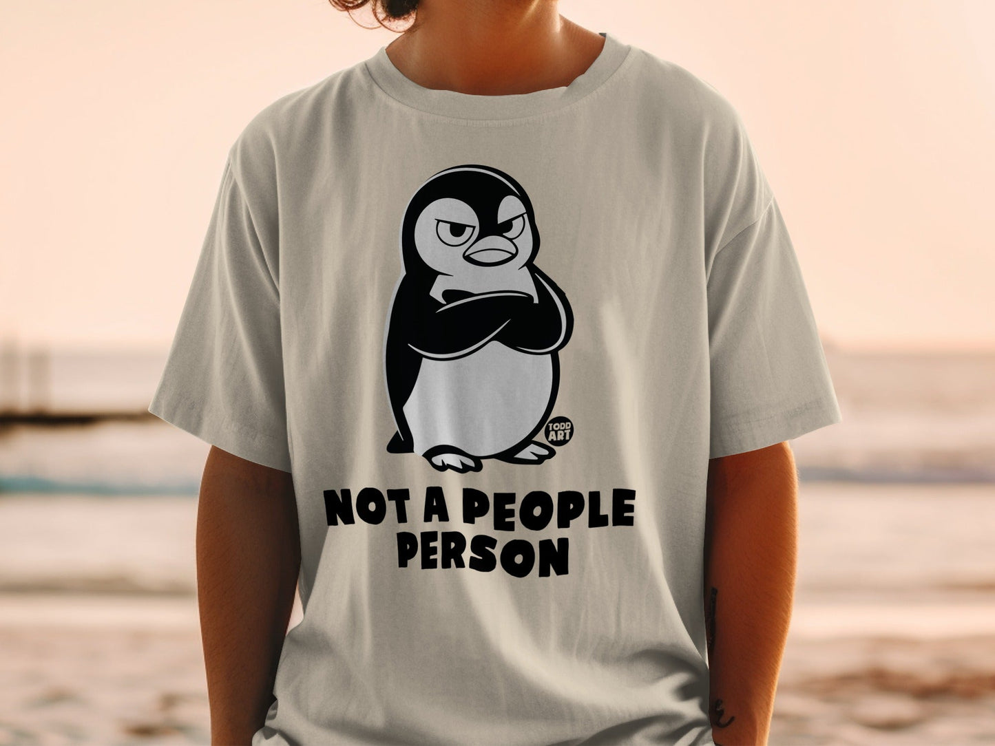 T-shirt with cartoon penguin arms crossed and text "NOT A PEOPLE PERSON".