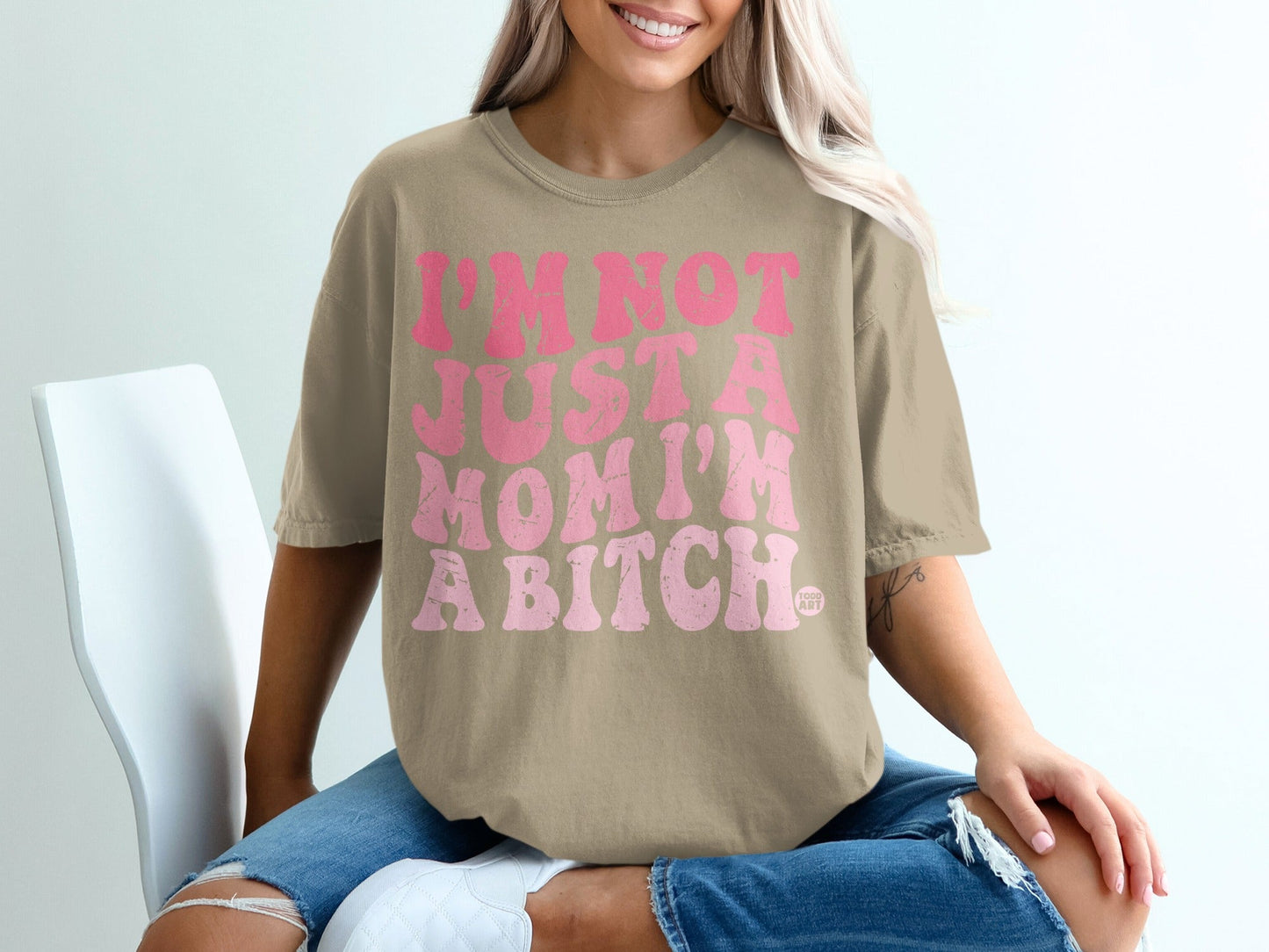 Tan t-shirt with pink text saying "I'm not just a mom I'm a bitch."