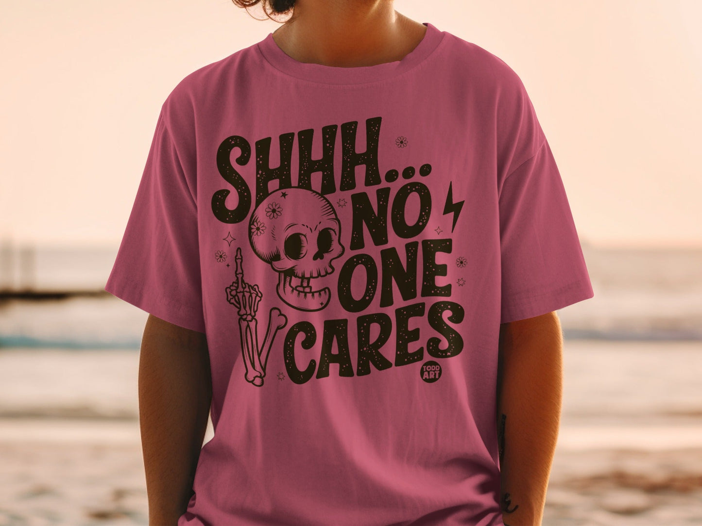 Pink t-shirt with "SHHH... NO ONE CARES" and skull graphic.