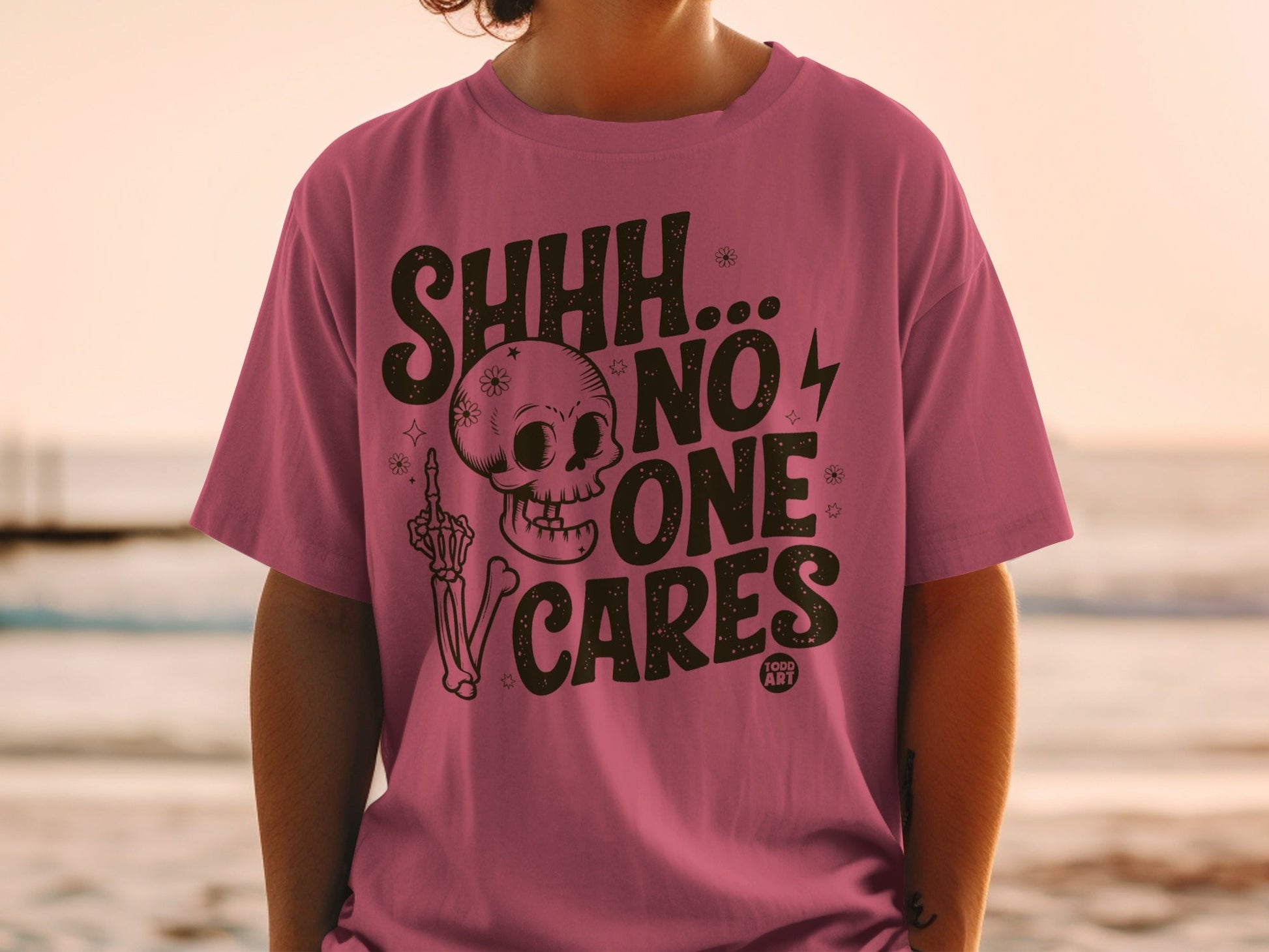 Pink t-shirt with "SHHH... NO ONE CARES" and skull graphic.